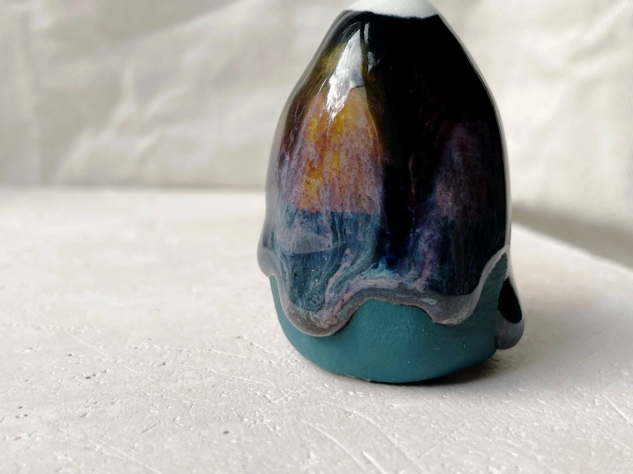 Black, purple, green and blue handmade figurative ceramic sculpture with glossy drippy floating glaze