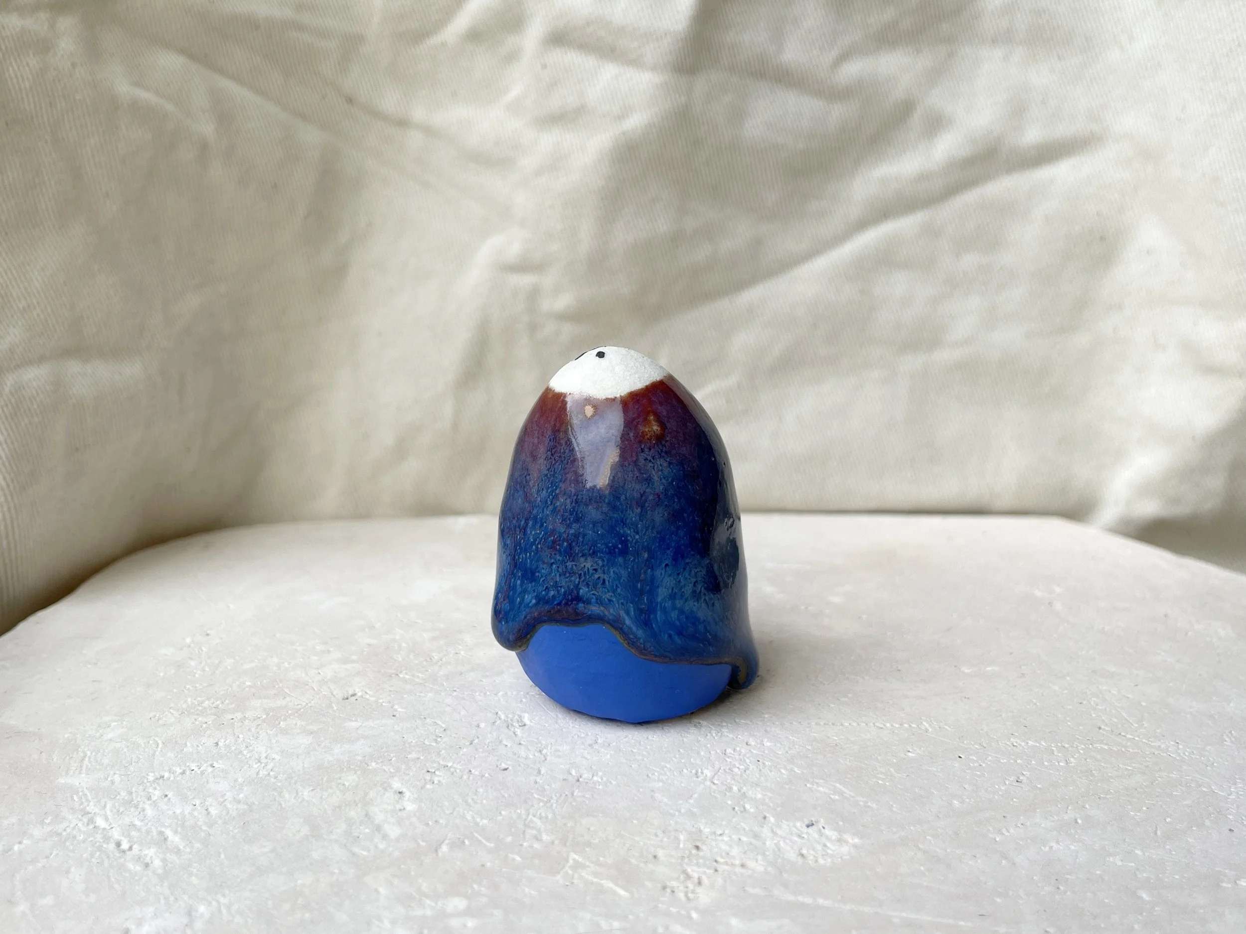 Red, blue and gold handmade figurative ceramic sculpture with underglaze and drippy runny glaze