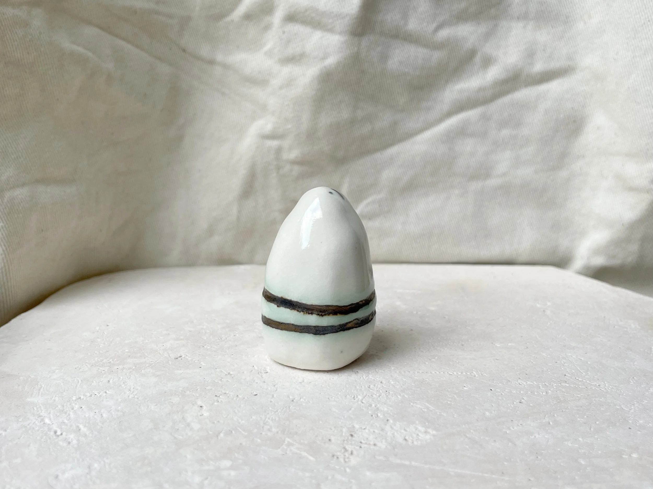 White and gold glossy handmade figurative ceramic sculpture with metallic glaze and hint of green