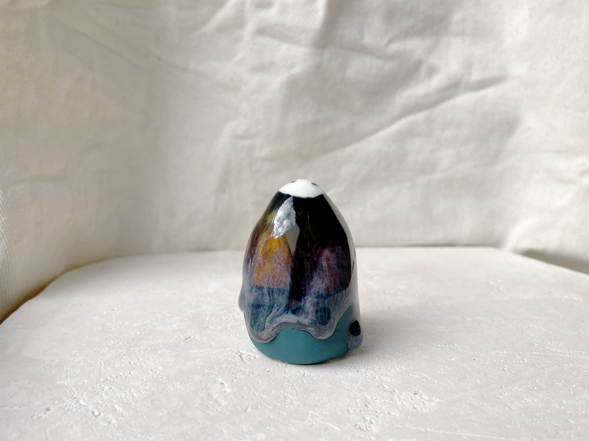 Black, purple, green and blue handmade figurative ceramic sculpture with glossy drippy floating glaze