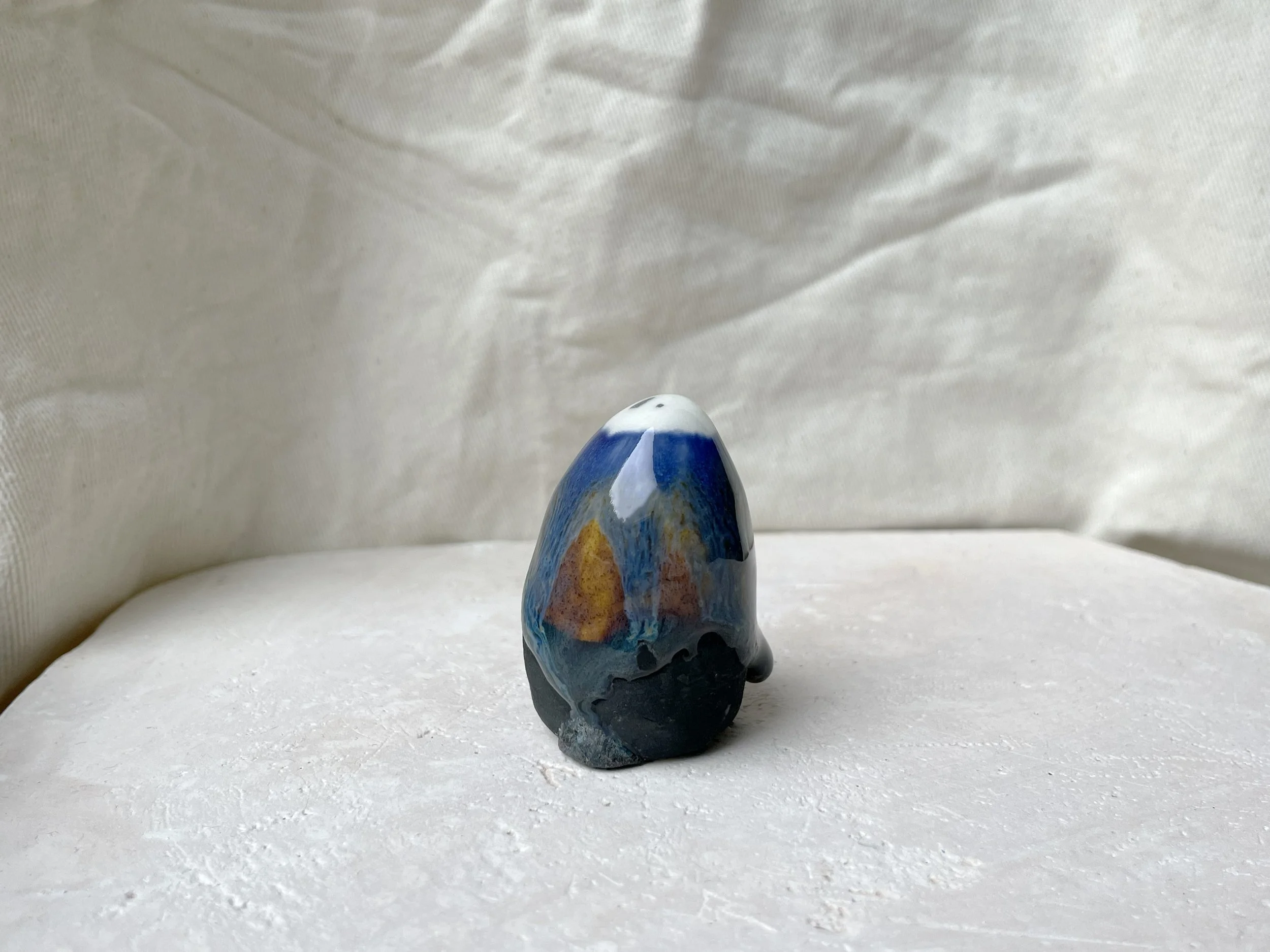 Blue, orange, black handmade figurative ceramic sculpture with glossy runny floating glaze