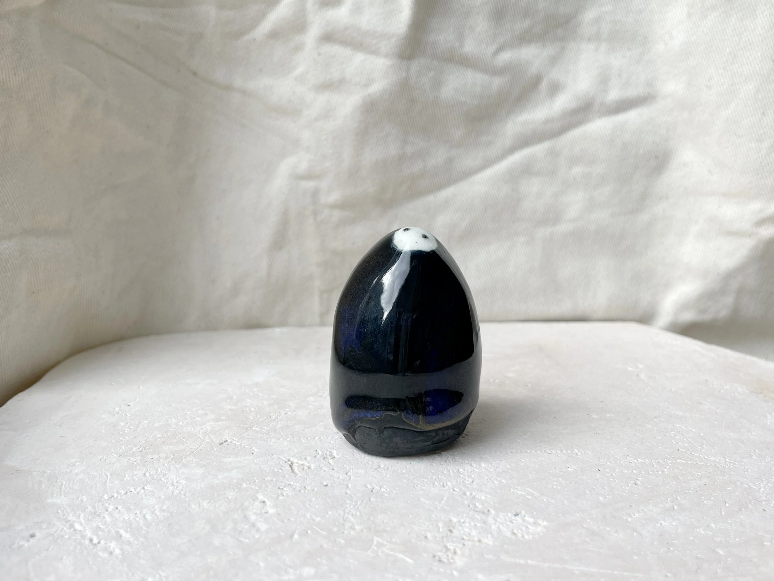 black, red, blue and gold handmade figurative ceramic sculpture with glossy floating glaze