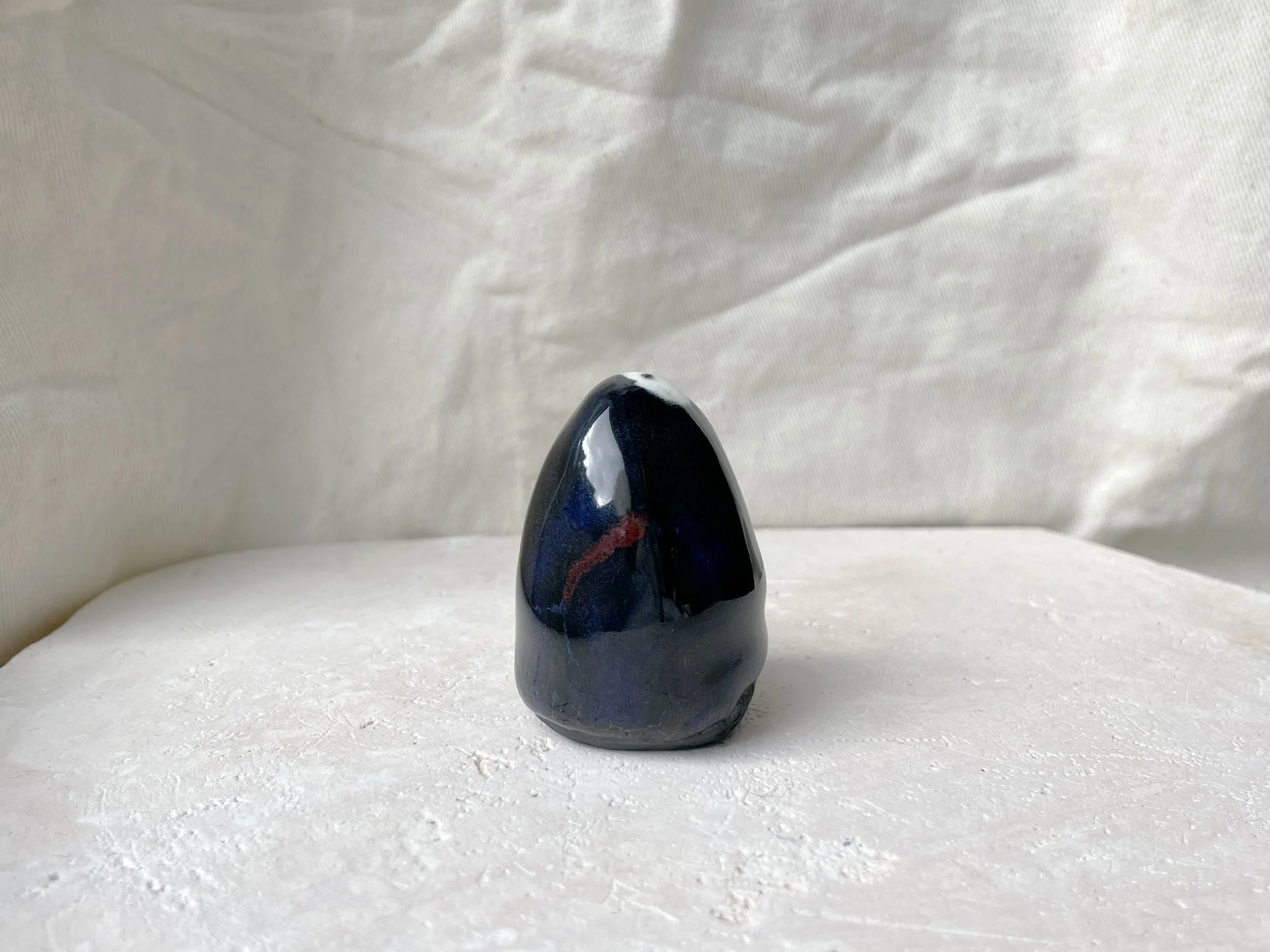 black, red, blue and gold handmade figurative ceramic sculpture with glossy floating glaze