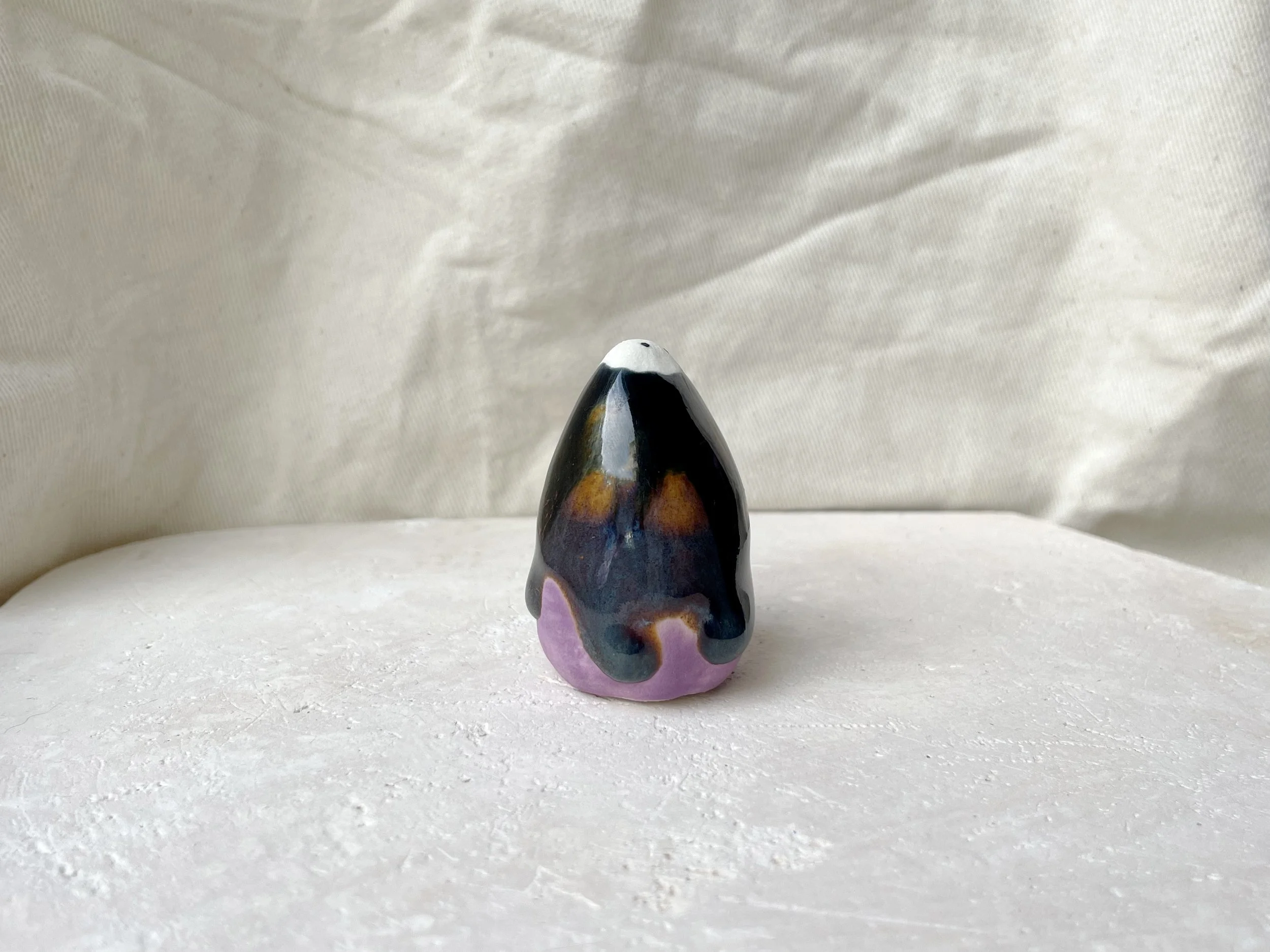Purple, black, orange, blue handmade figurative ceramic sculpture with underglaze and drippy runny glaze