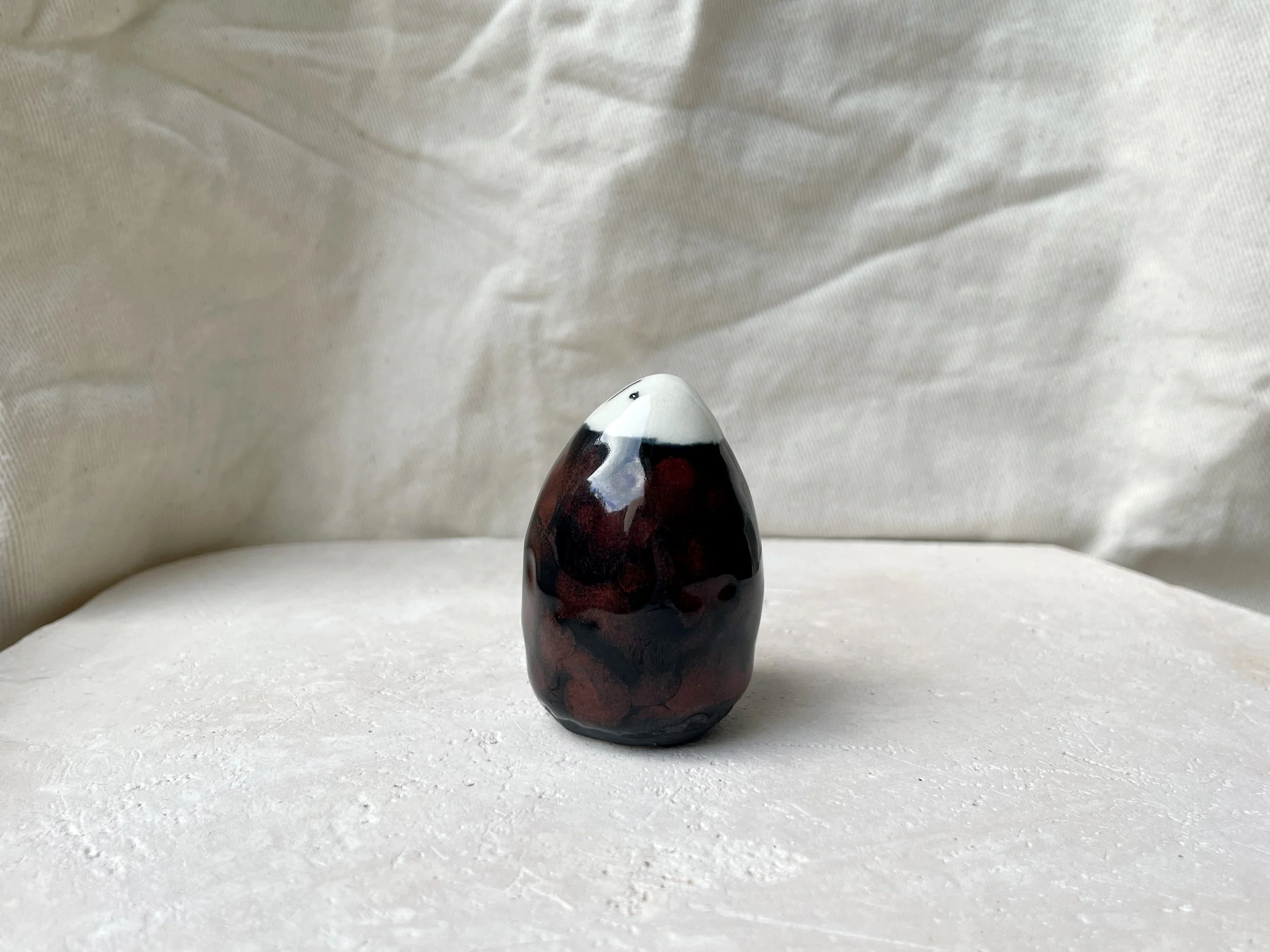 Black and red handmade figurative ceramic sculpture with glossy floating glaze