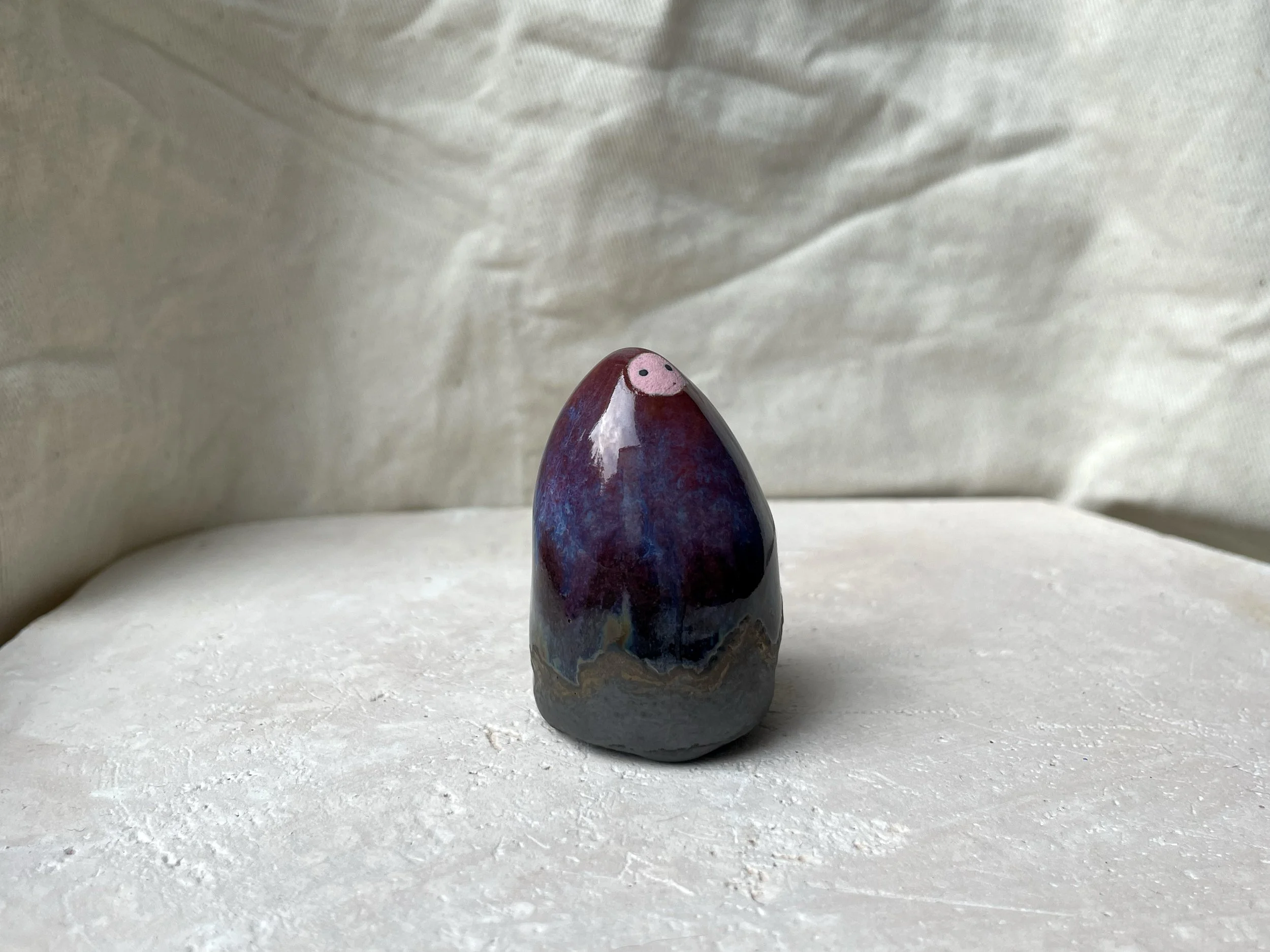 Red, purple, black, gold and pink handmade figurative ceramic sculpture with glossy drippy floating glaze