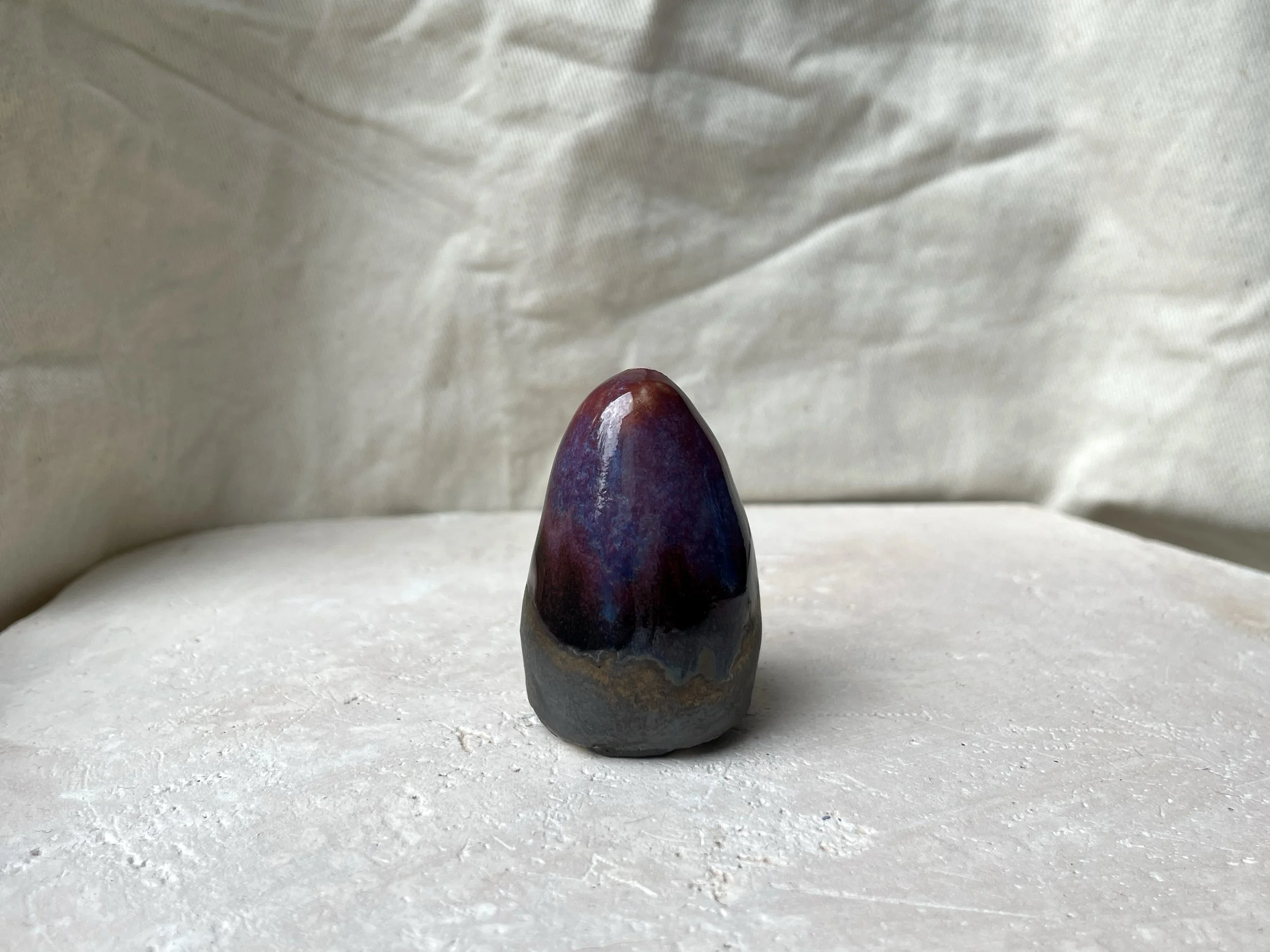 Red, purple, black, gold and pink handmade figurative ceramic sculpture with glossy drippy floating glaze