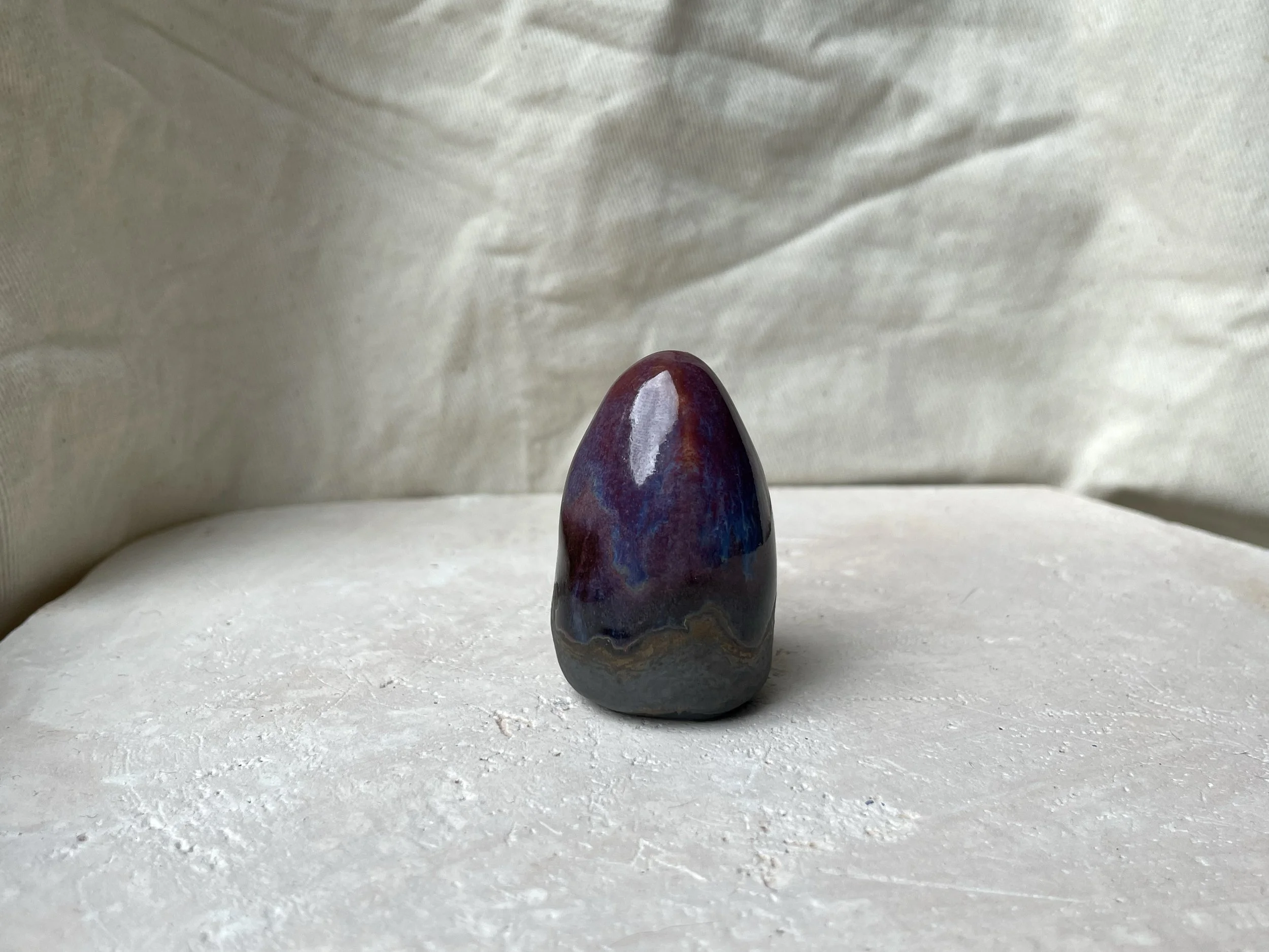 Red, purple, black, gold and pink handmade figurative ceramic sculpture with glossy drippy floating glaze