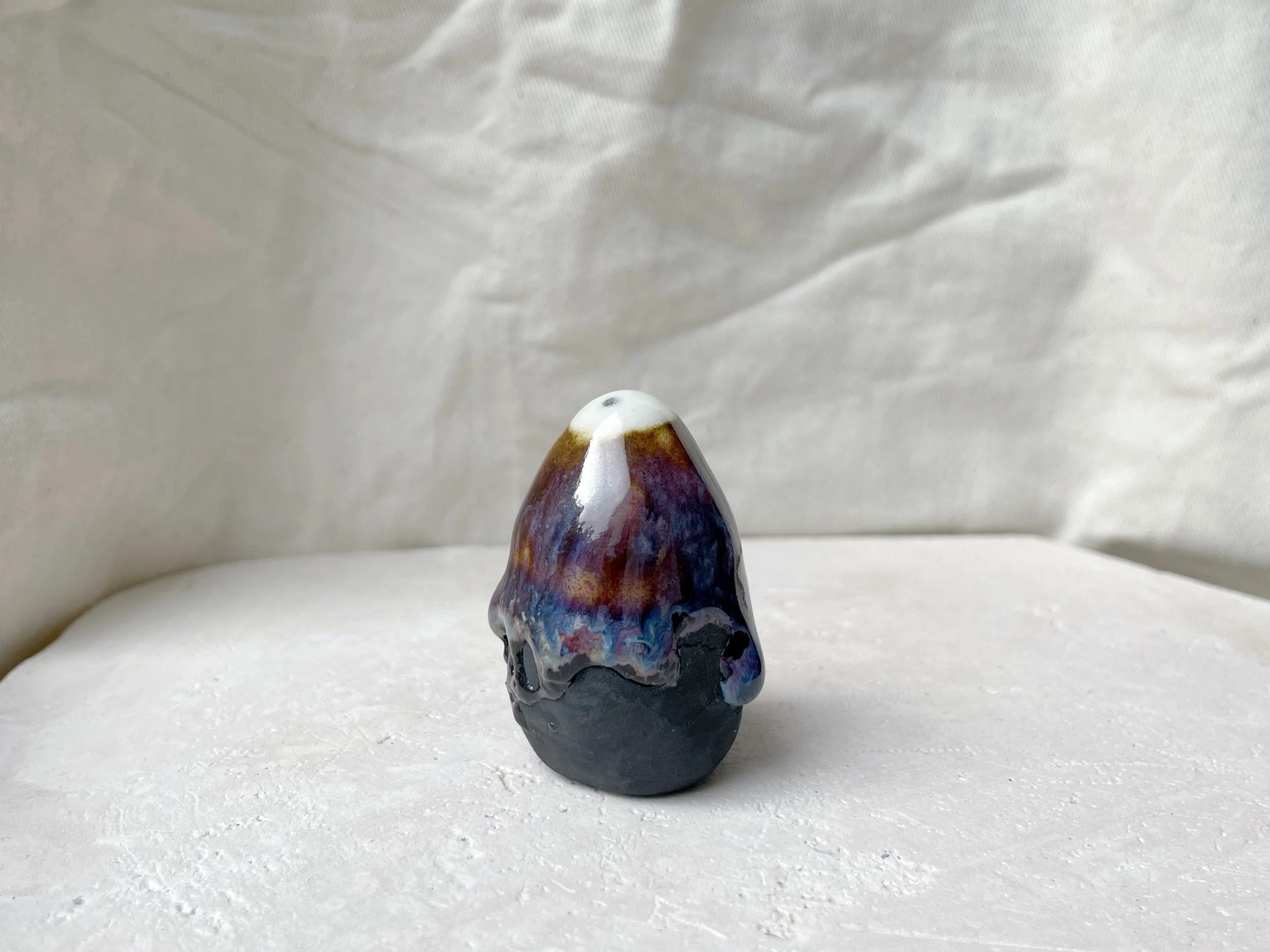 Brown, purple, blue and black handmade figurative ceramic sculpture with glossy runny floating glaze
