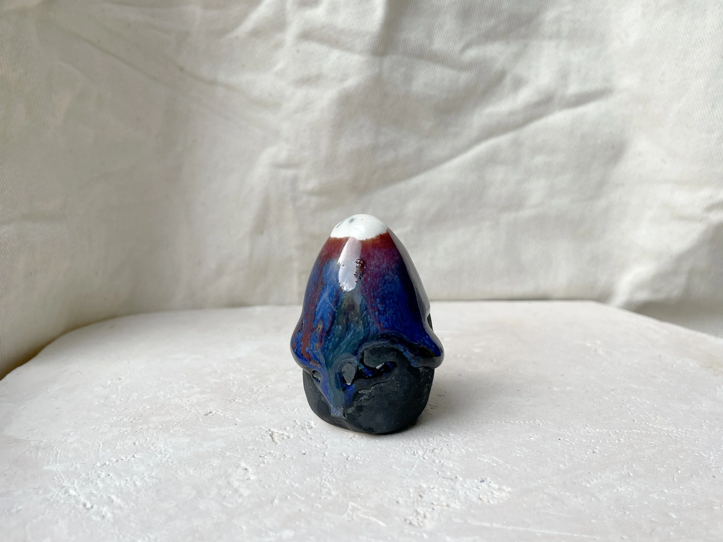 black, brown, red, blue and green handmade figurative ceramic sculpture with matte and glossy floating glaze