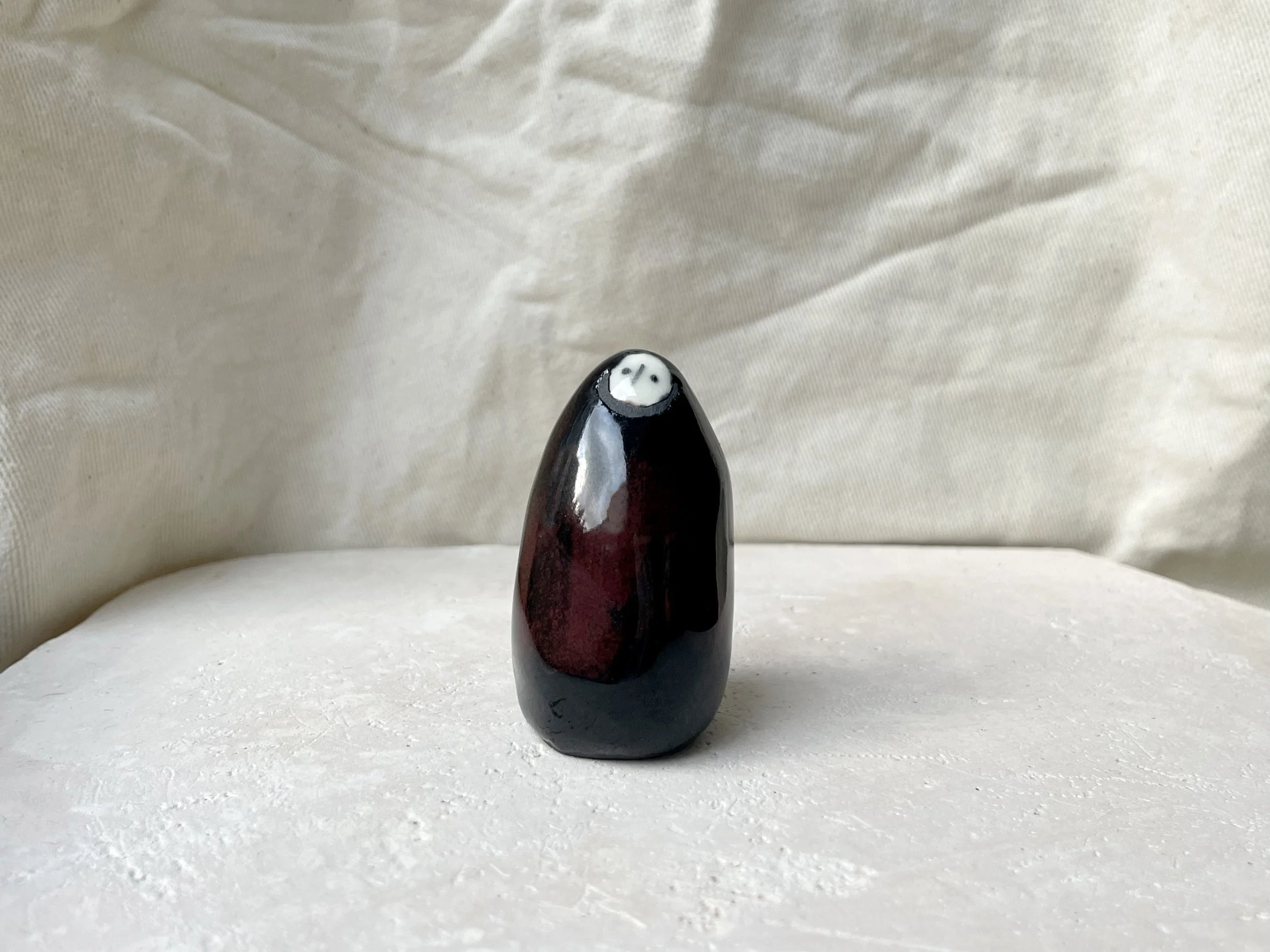 Black and red handmade figurative ceramic sculpture with glossy floating glaze