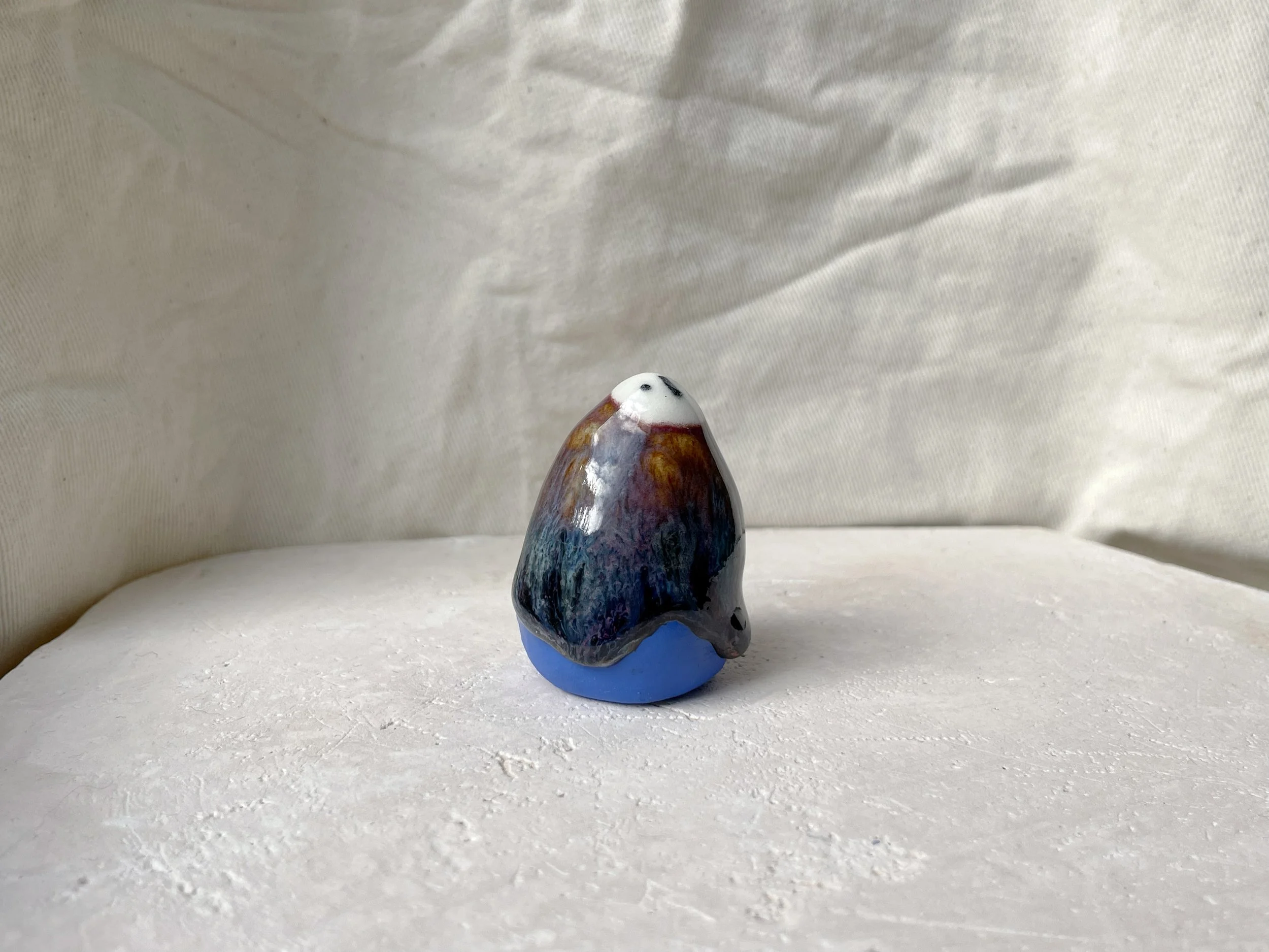 orange, purple, blue and black handmade figurative ceramic sculpture with glossy drippy floating glaze
