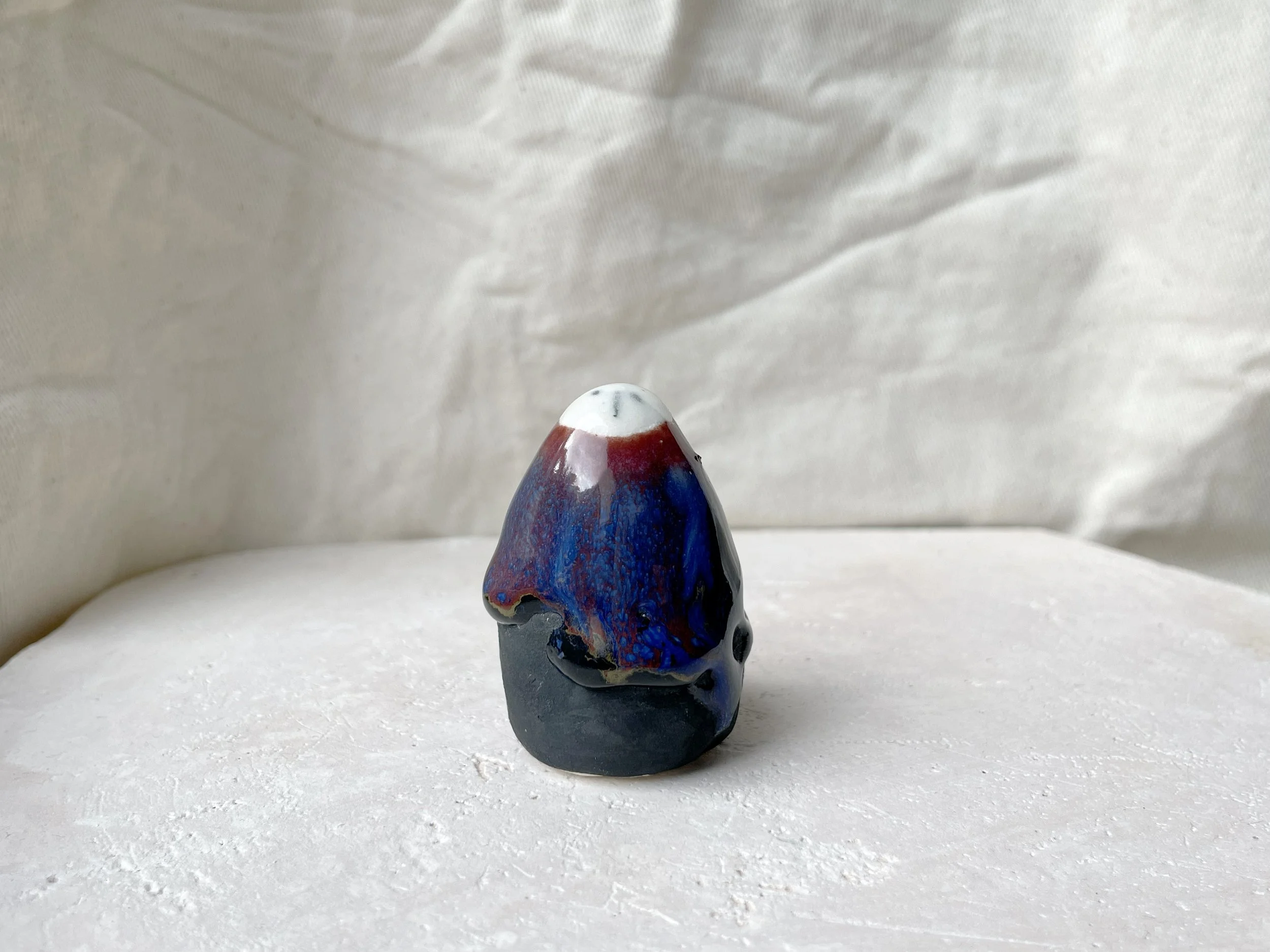 black, brown, red, blue and green handmade figurative ceramic sculpture with matte and glossy floating glaze