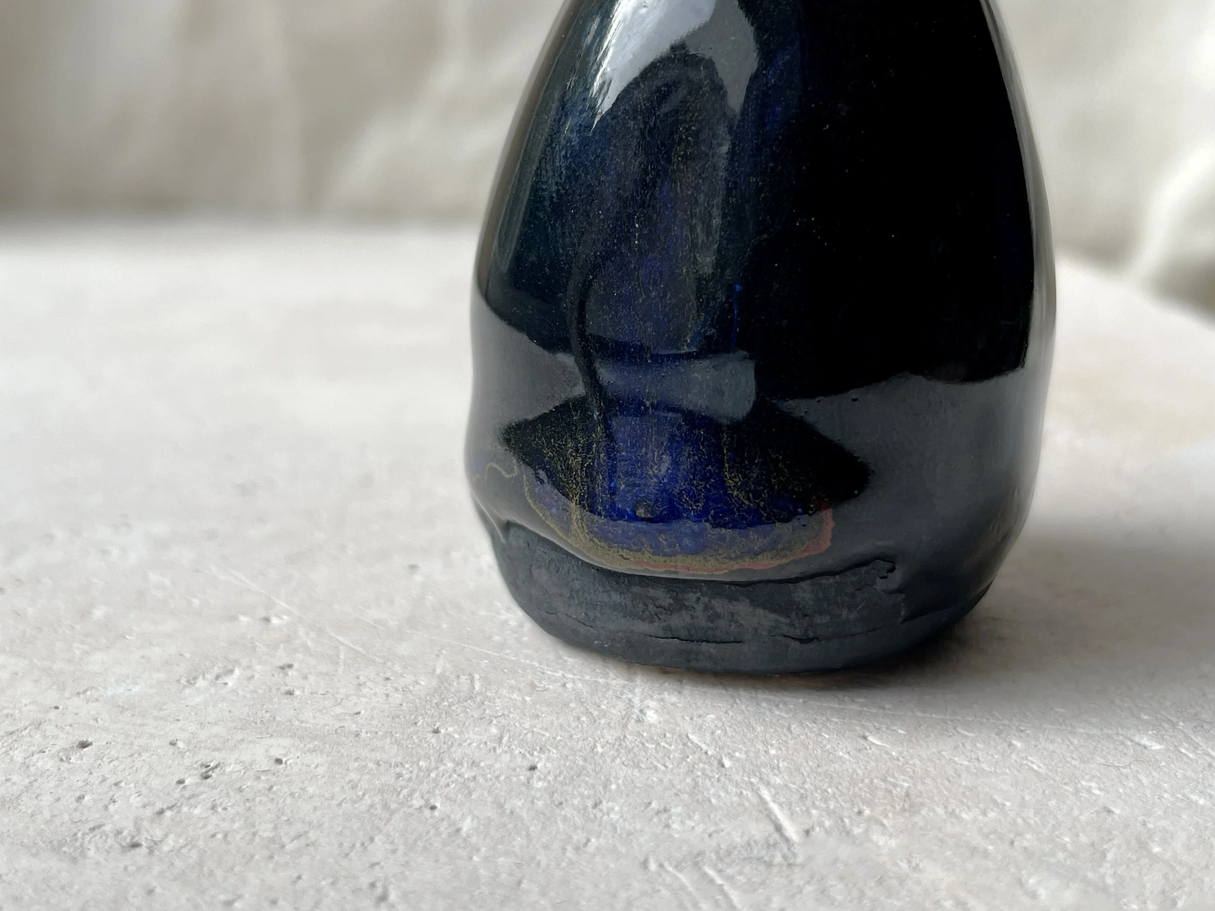 black, red, blue and gold handmade figurative ceramic sculpture with glossy floating glaze