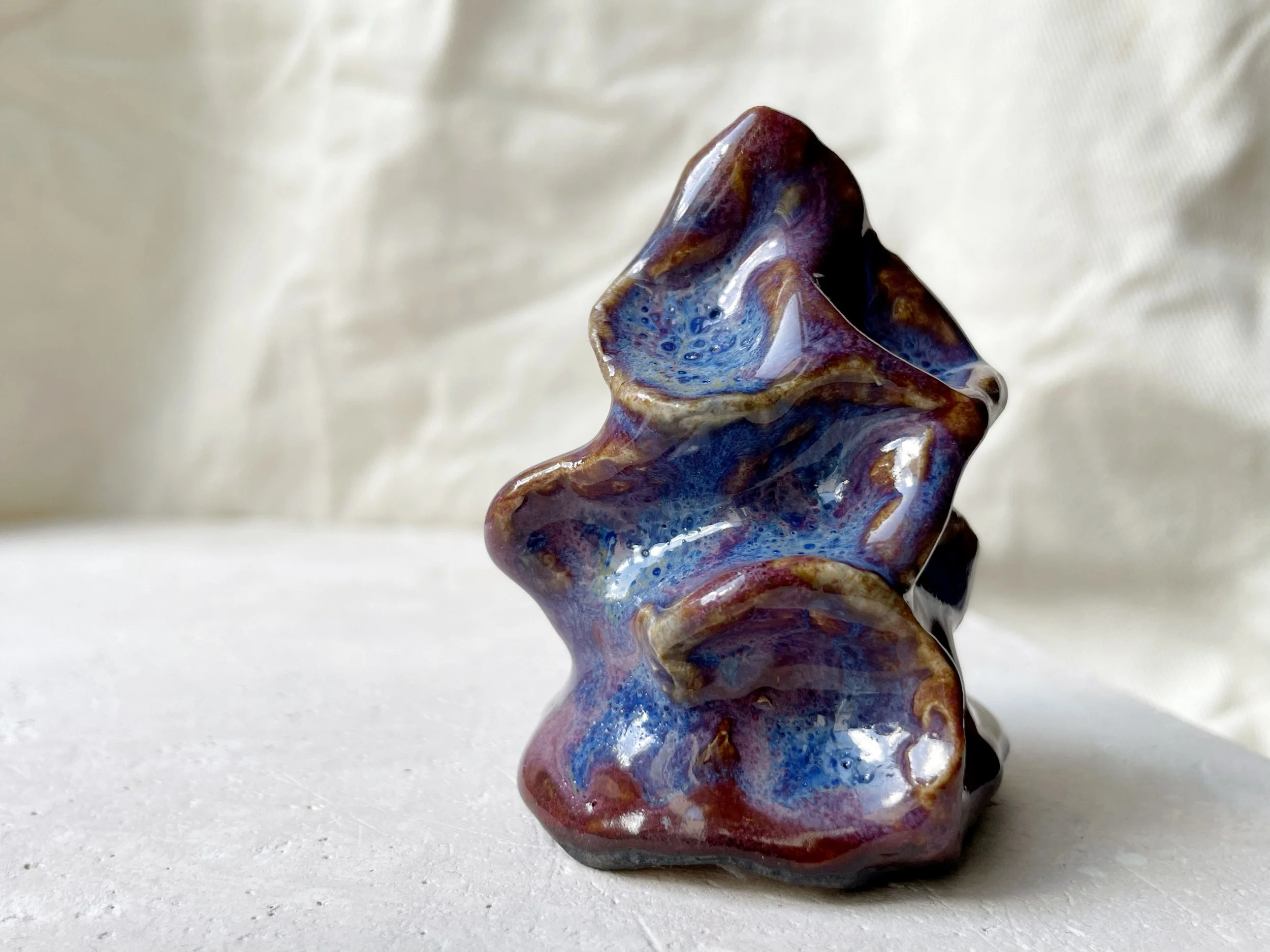 Blue, purple and red wavy handmade figurative ceramic sculpture with underglaze and runny glaze