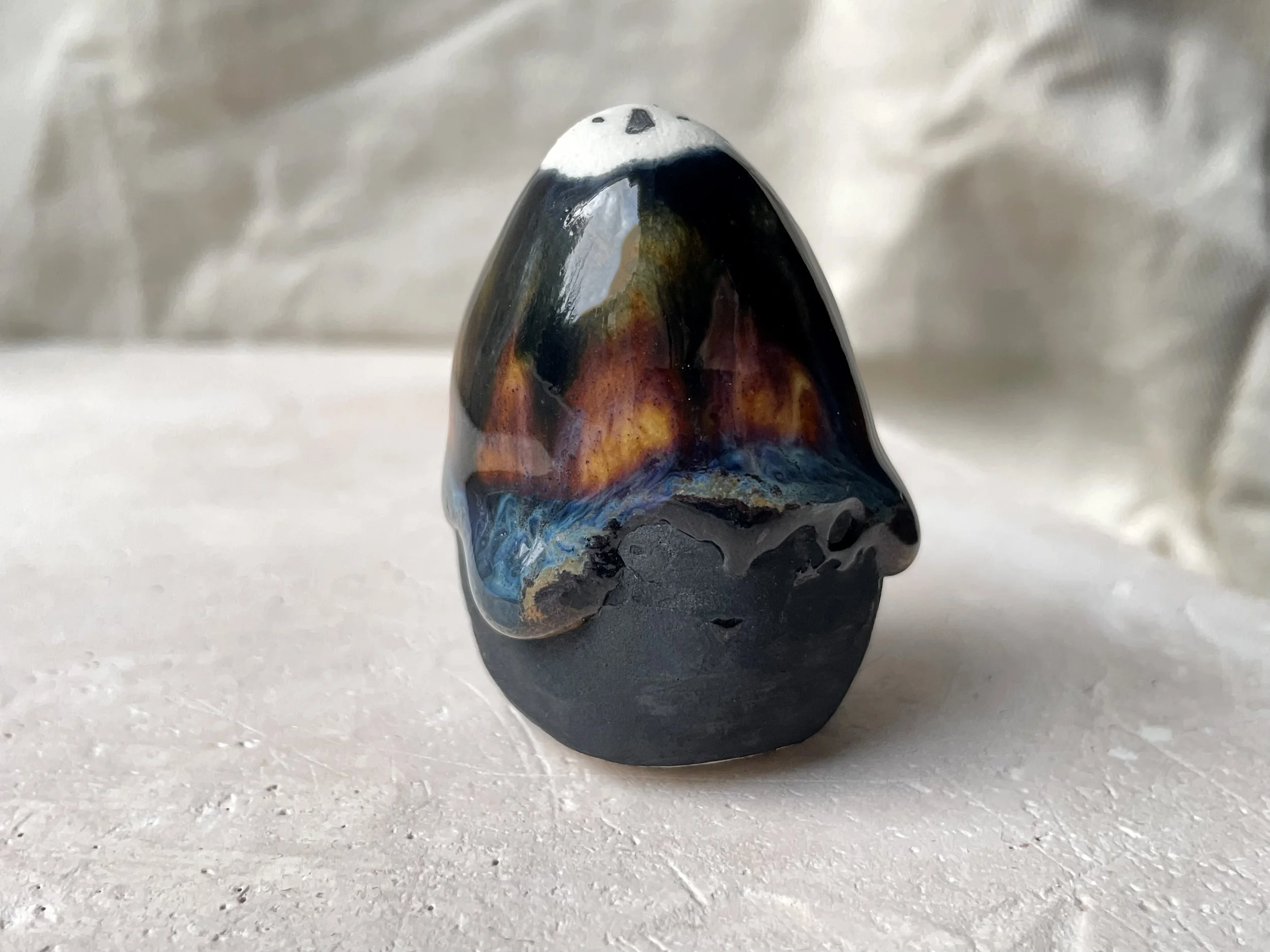 Black, orange and blue handmade figurative ceramic sculpture with underglaze and drippy float glaze