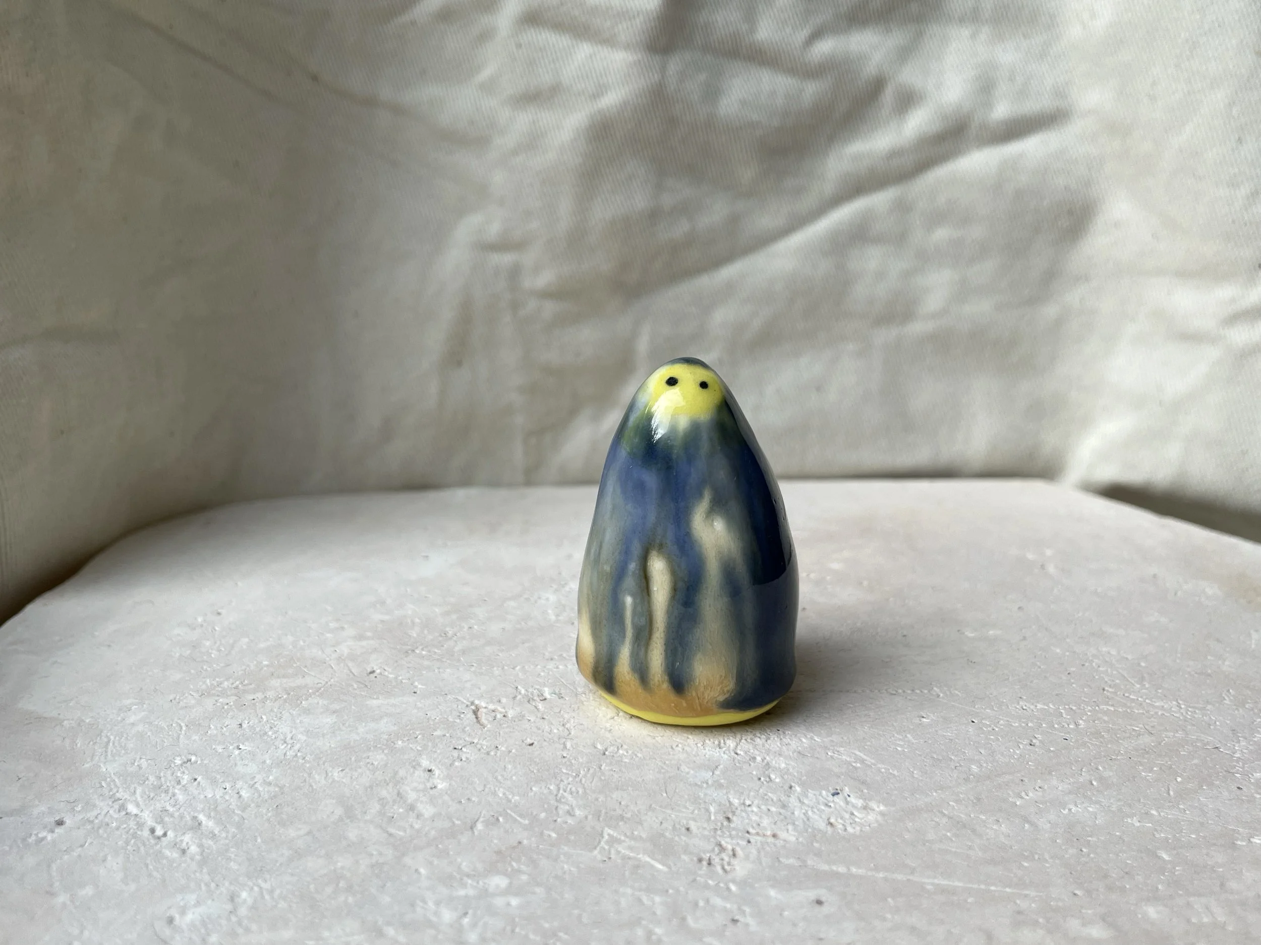 Yellow, blue and cream handmade figurative ceramic sculpture with glossy drippy glaze