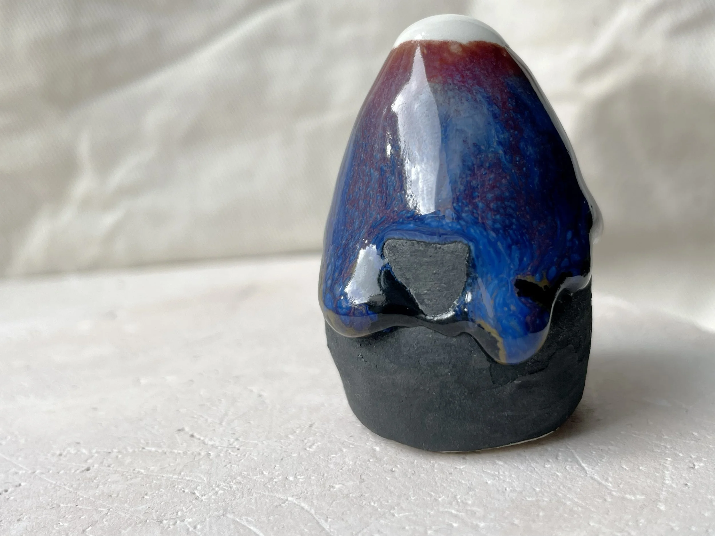 black, brown, red, blue and green handmade figurative ceramic sculpture with matte and glossy floating glaze