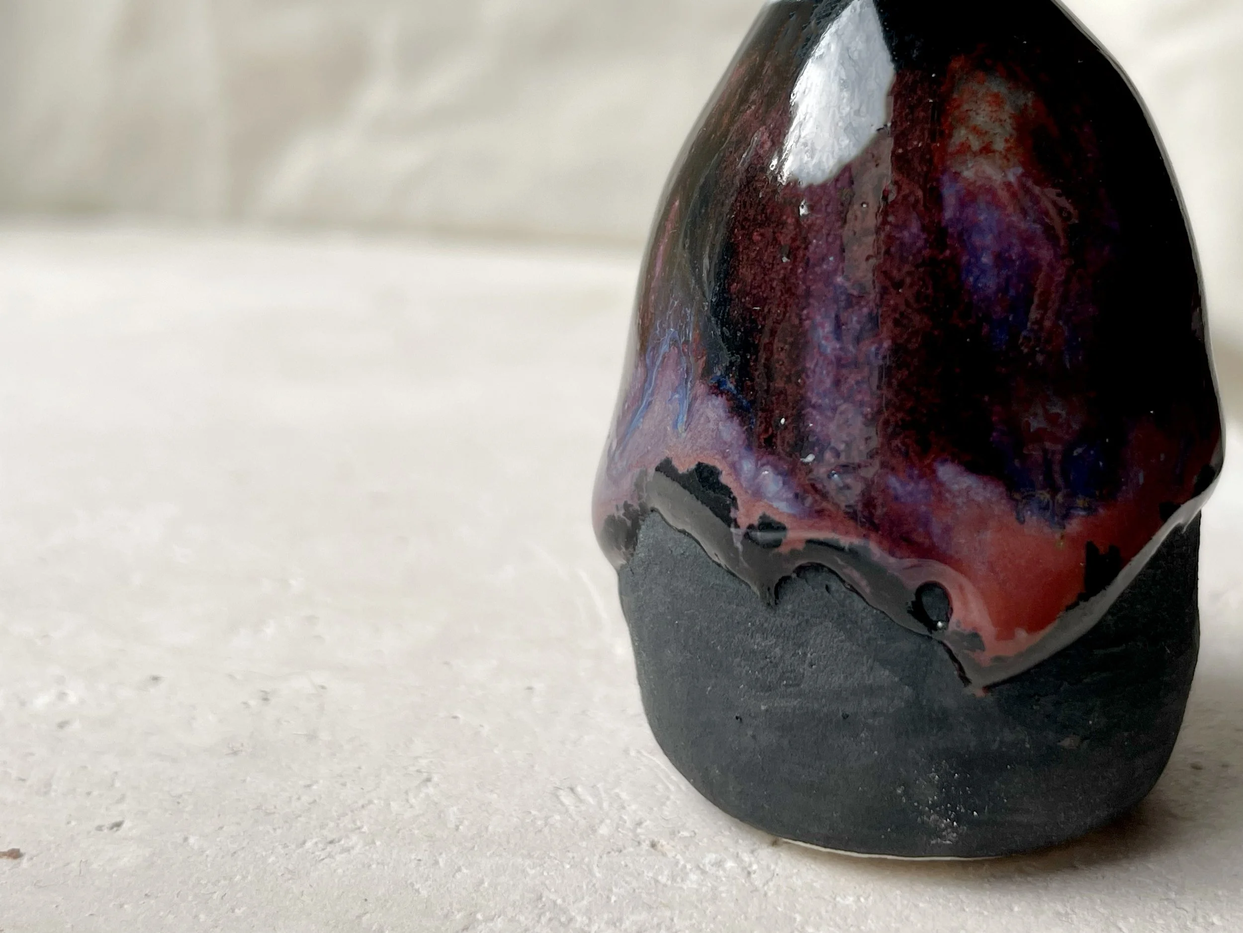 purple, black and red handmade figurative ceramic sculpture with glossy drippy floating glaze