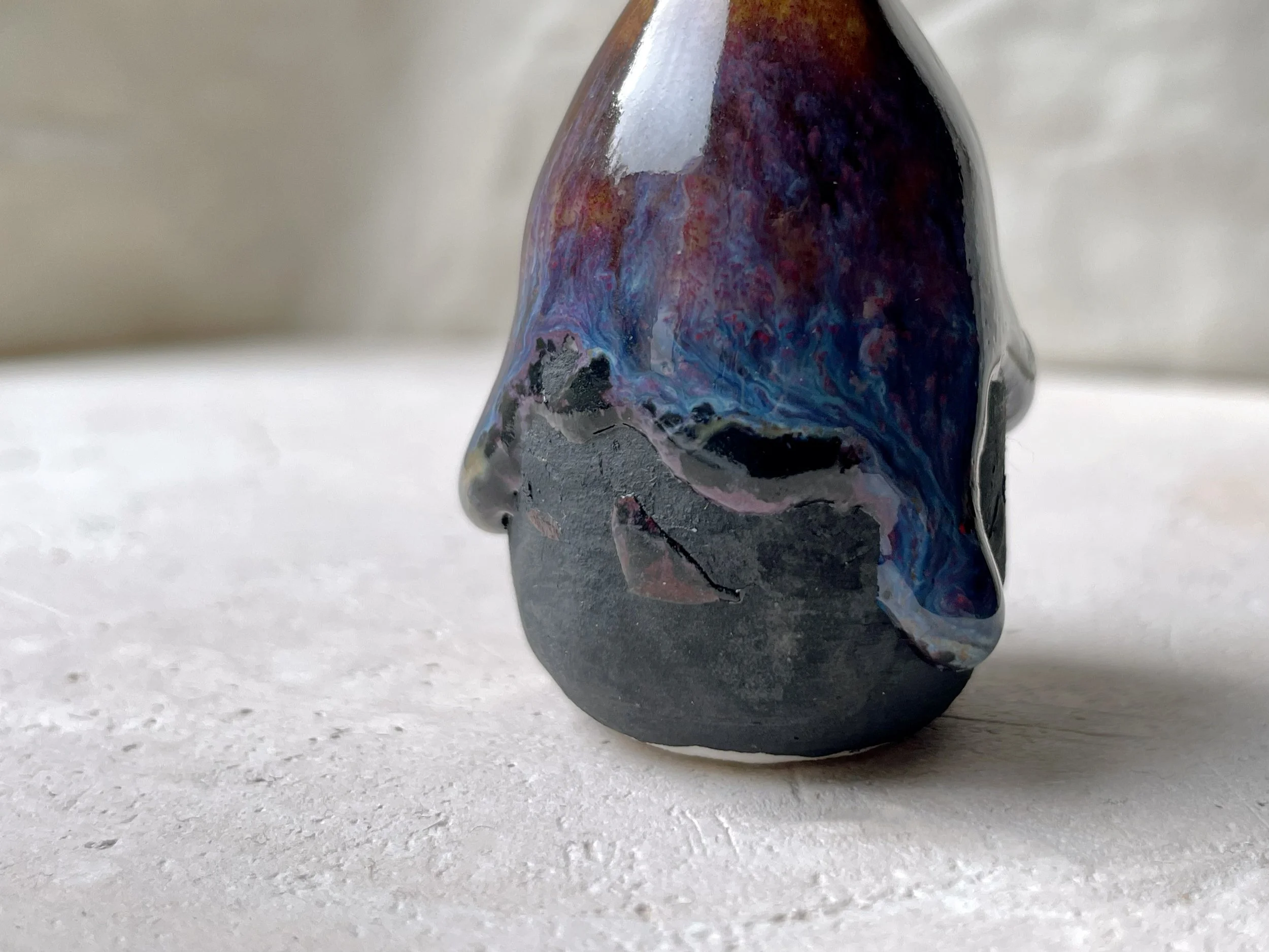 Brown, purple, blue and black handmade figurative ceramic sculpture with glossy runny floating glaze