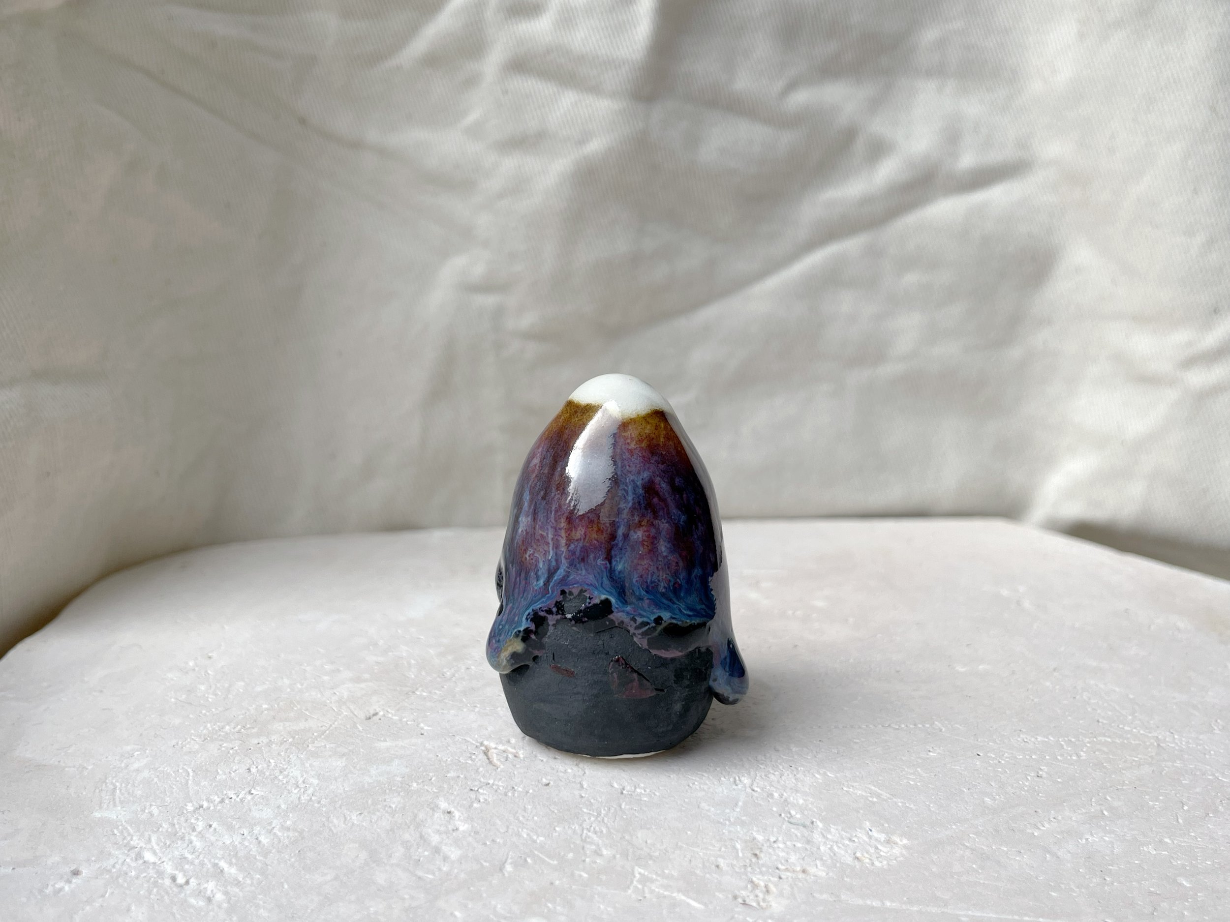 Brown, purple, blue and black handmade figurative ceramic sculpture with glossy runny floating glaze