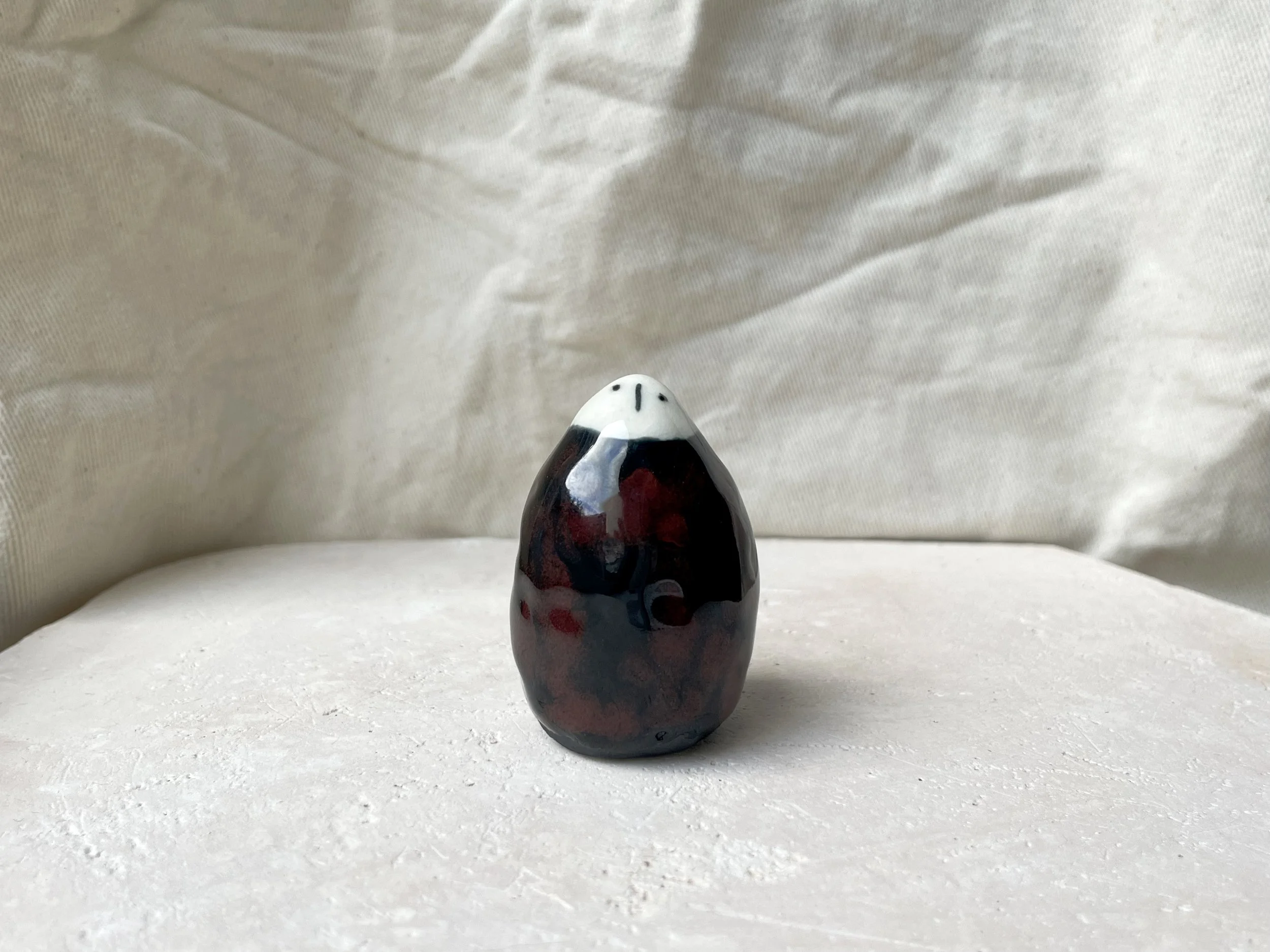 Black and red handmade figurative ceramic sculpture with glossy floating glaze