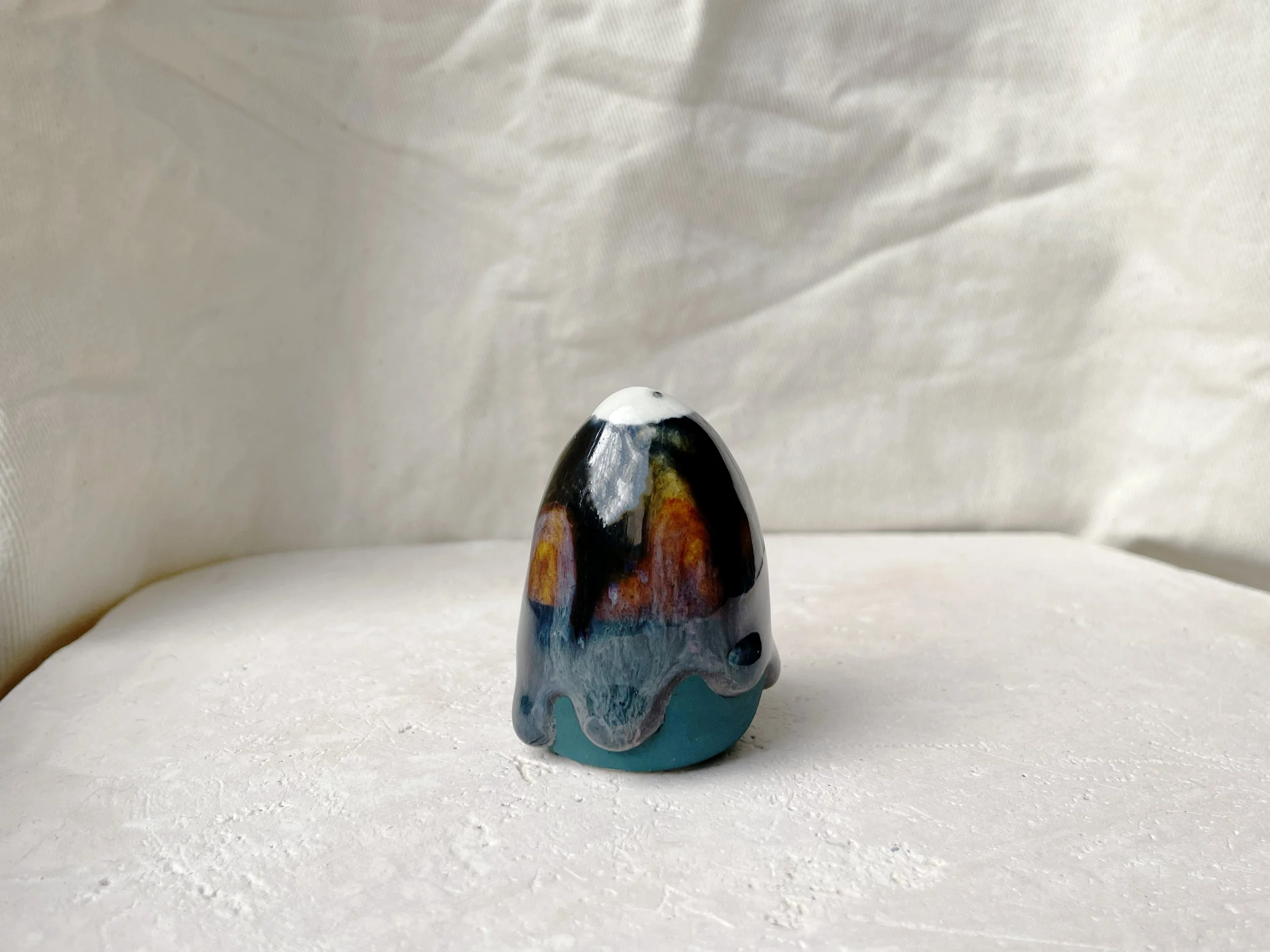 Black, purple, green and blue handmade figurative ceramic sculpture with glossy drippy floating glaze