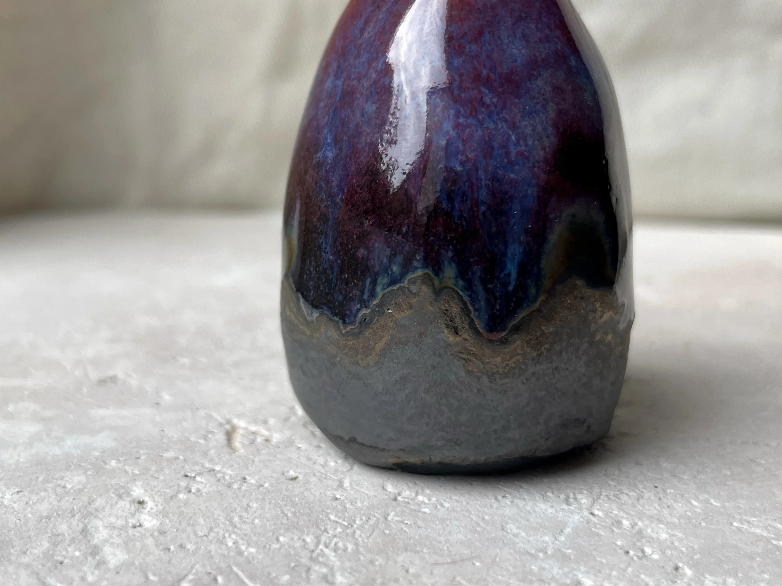 Red, purple, black, gold and pink handmade figurative ceramic sculpture with glossy drippy floating glaze