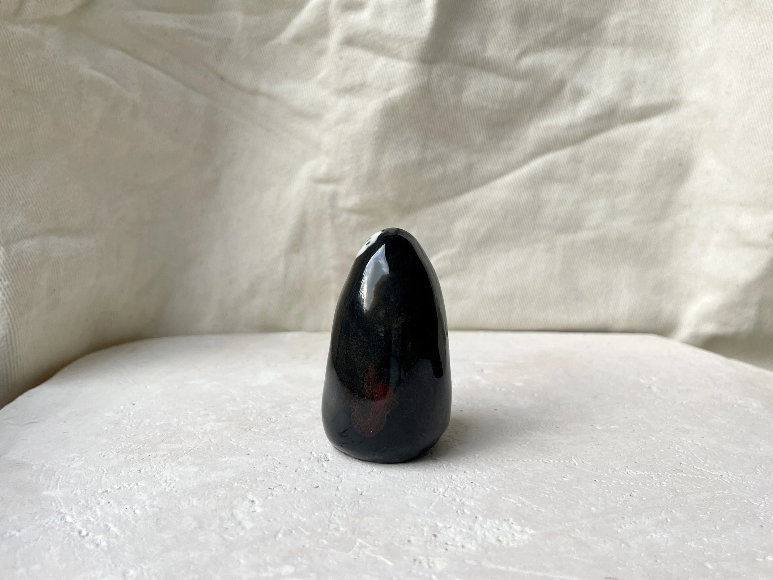 Black and red handmade figurative ceramic sculpture with glossy floating glaze