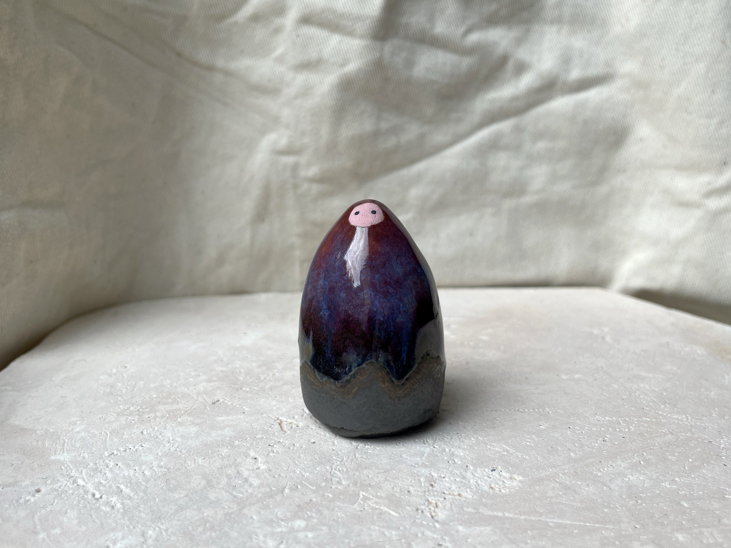 Red, purple, black, gold and pink handmade figurative ceramic sculpture with glossy drippy floating glaze