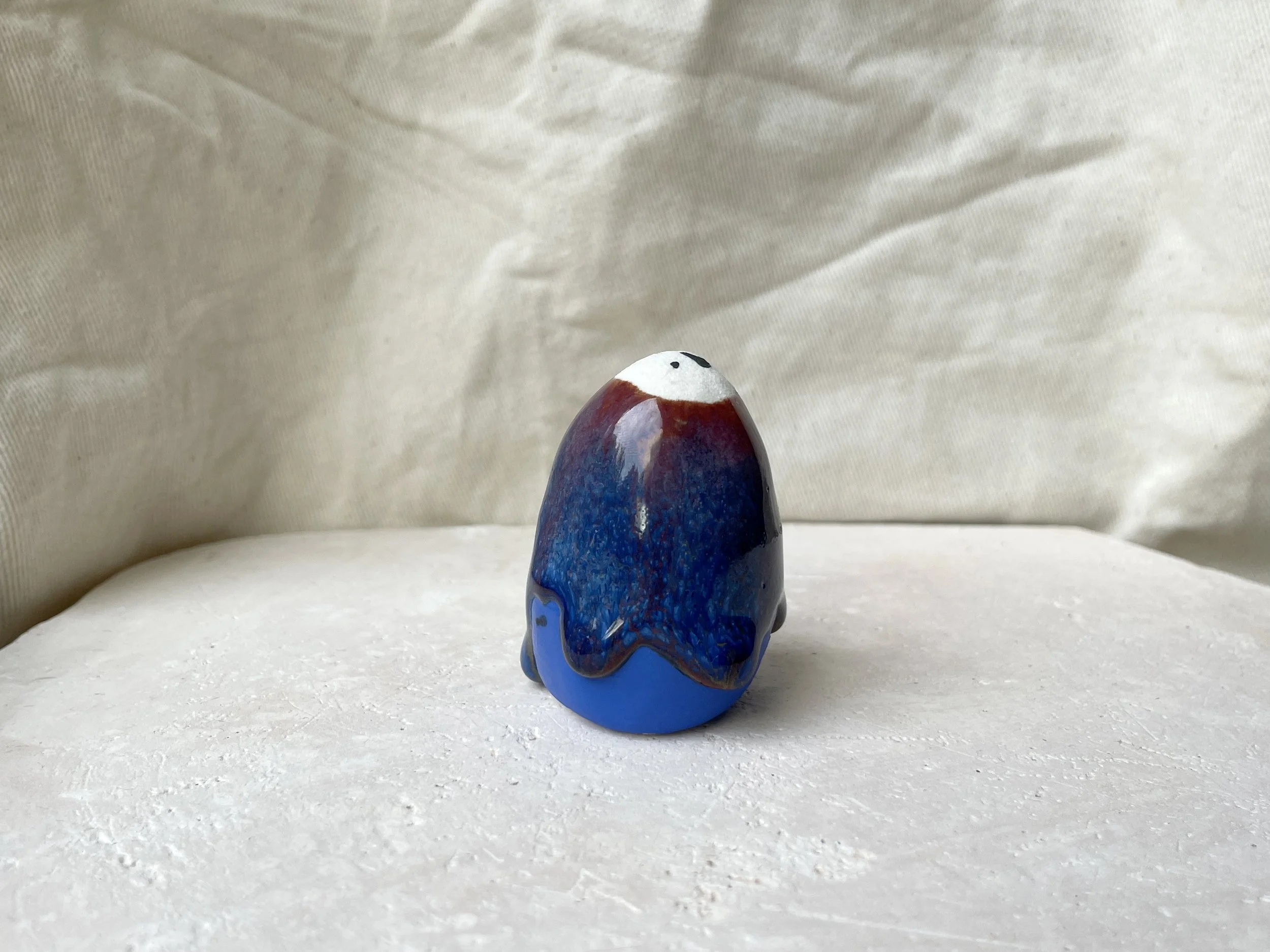 Red, blue and gold handmade figurative ceramic sculpture with underglaze and drippy runny glaze