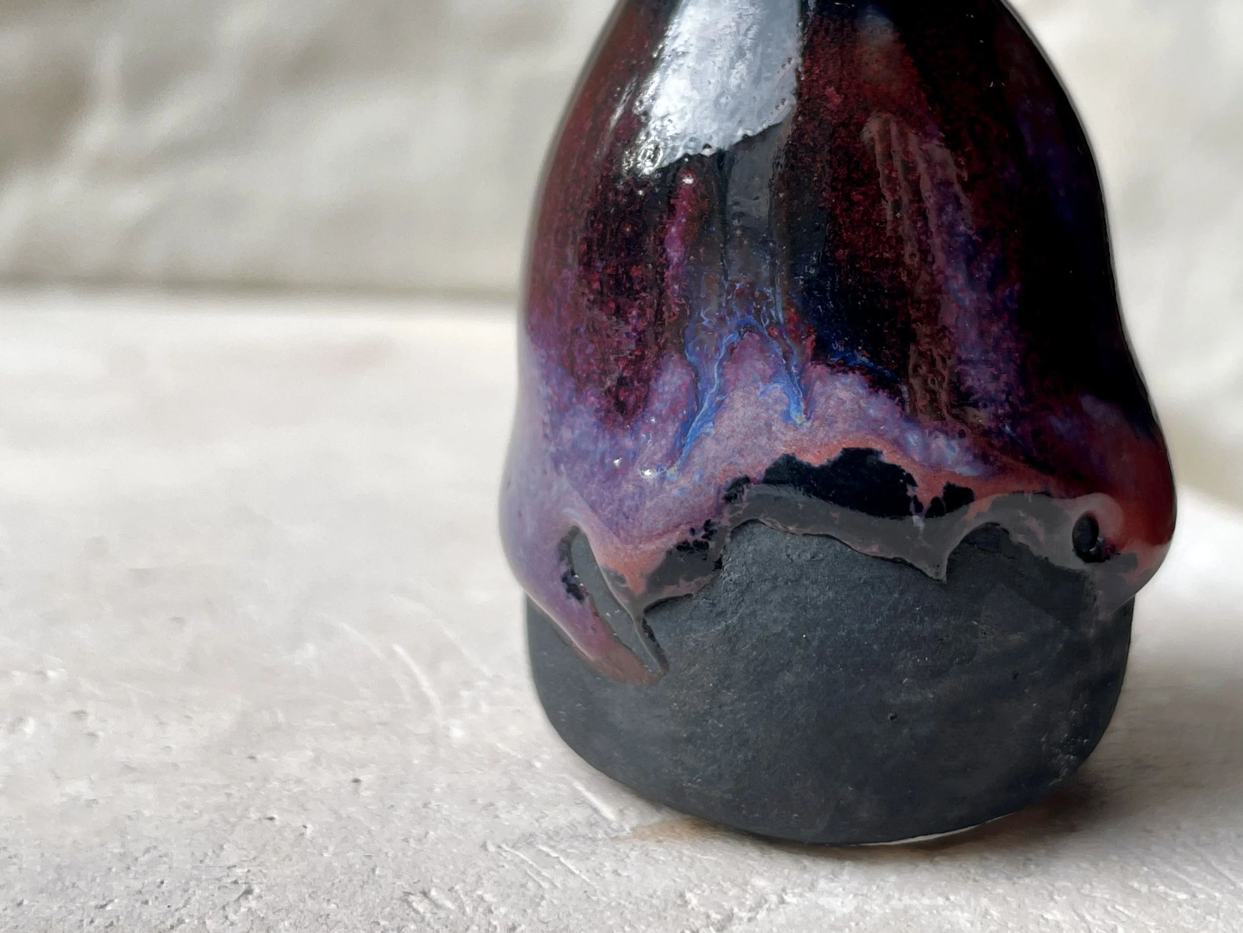 purple, black and red handmade figurative ceramic sculpture with glossy drippy floating glaze