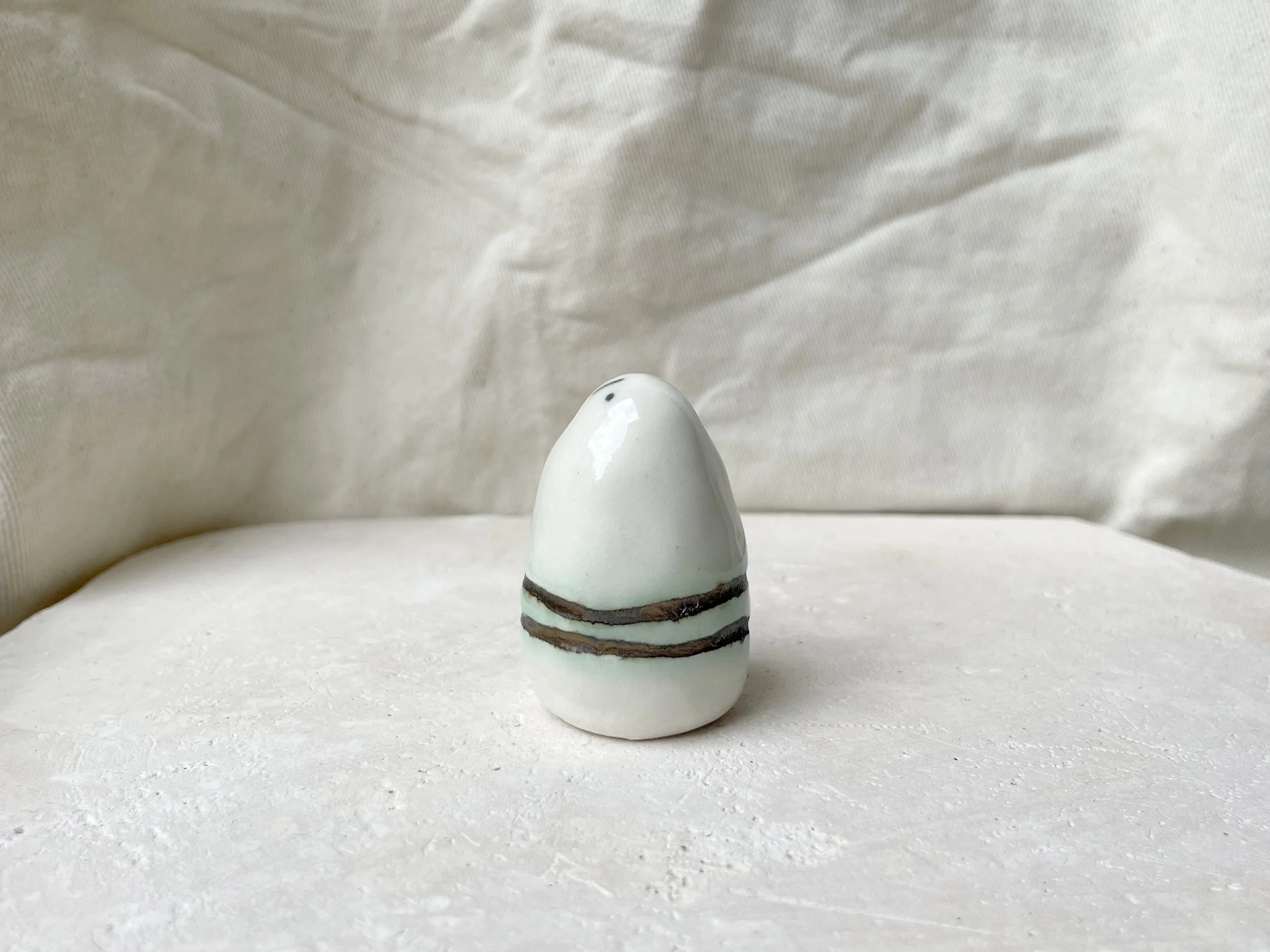 White and gold glossy handmade figurative ceramic sculpture with metallic glaze and hint of green