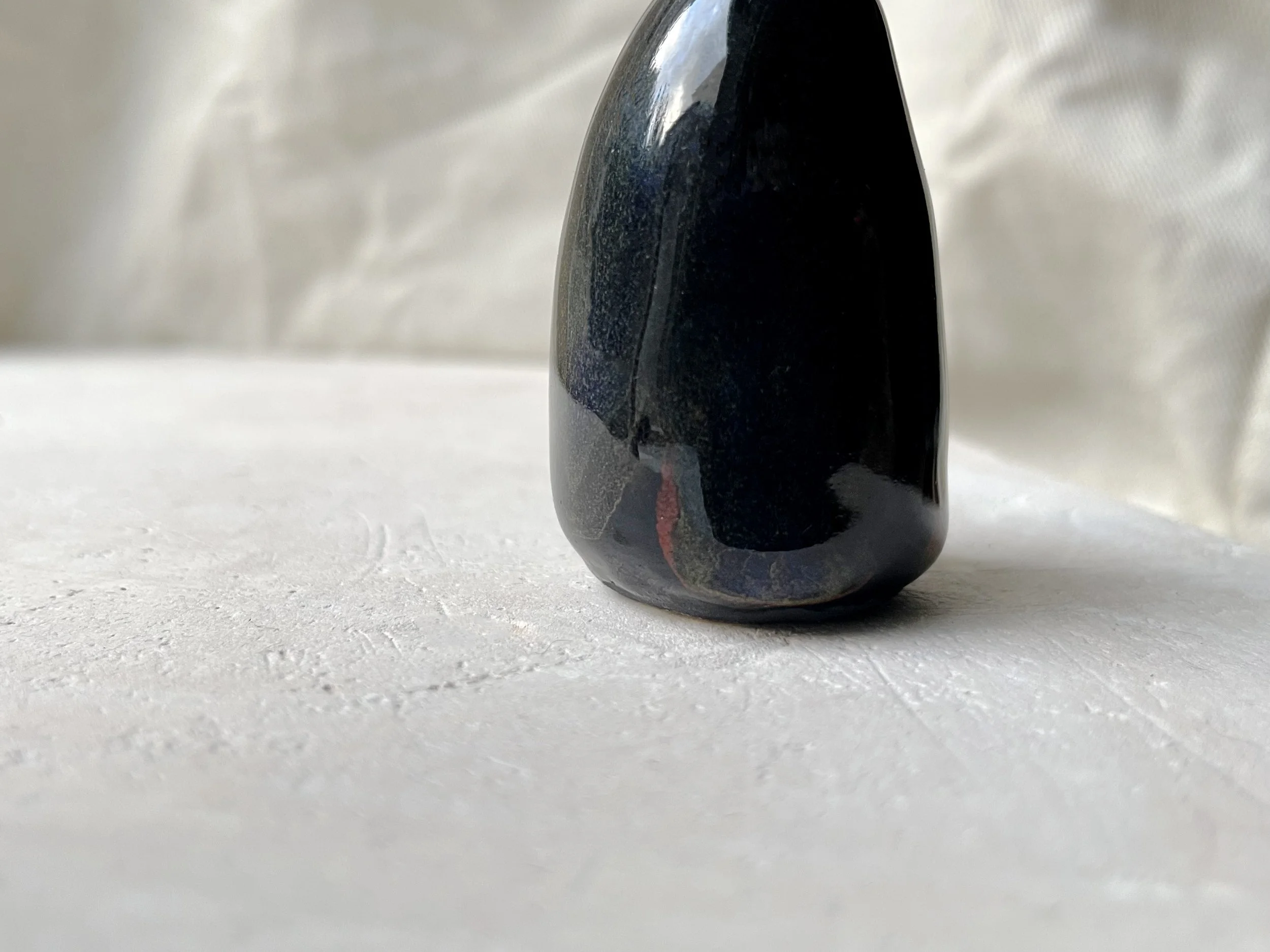 Black and red handmade figurative ceramic sculpture with glossy floating glaze