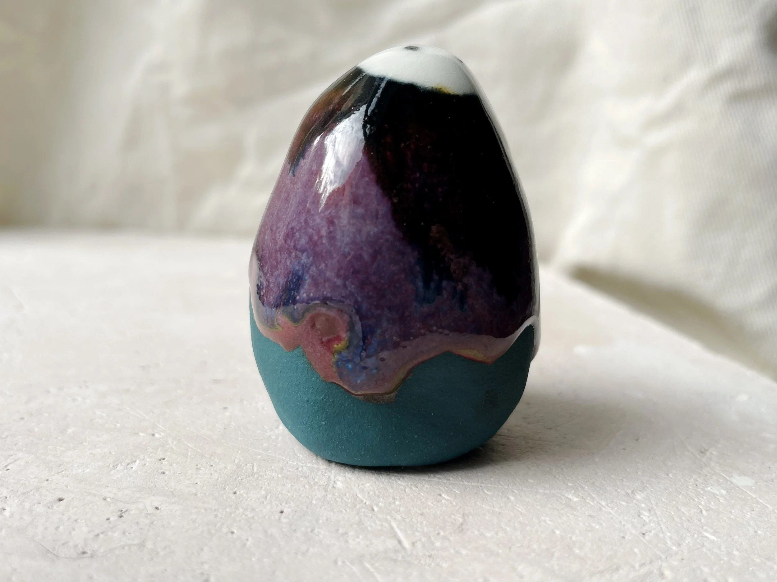 Black, purple, green and red handmade figurative ceramic sculpture with glossy drippy floating glaze