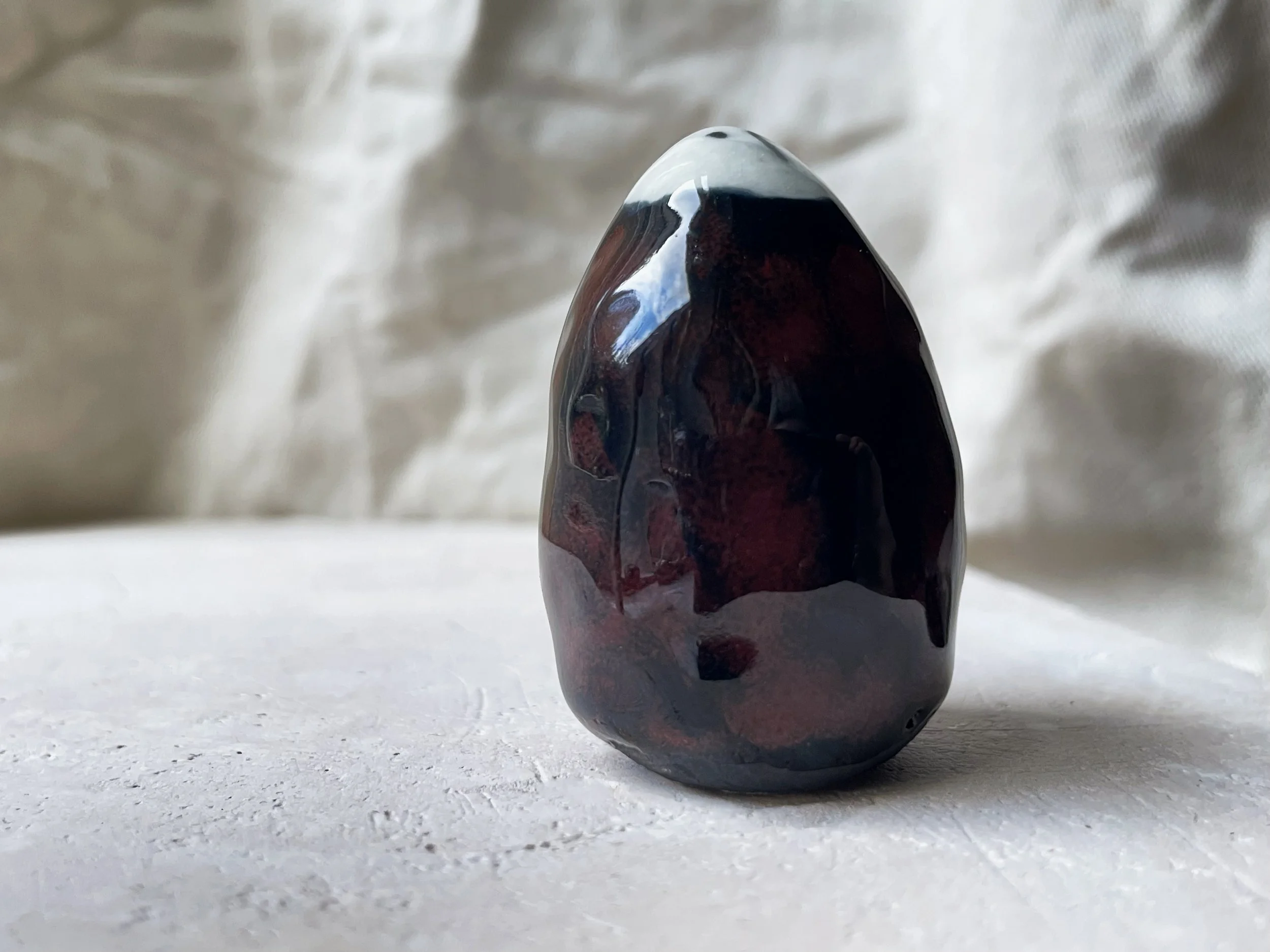 Black and red handmade figurative ceramic sculpture with glossy floating glaze