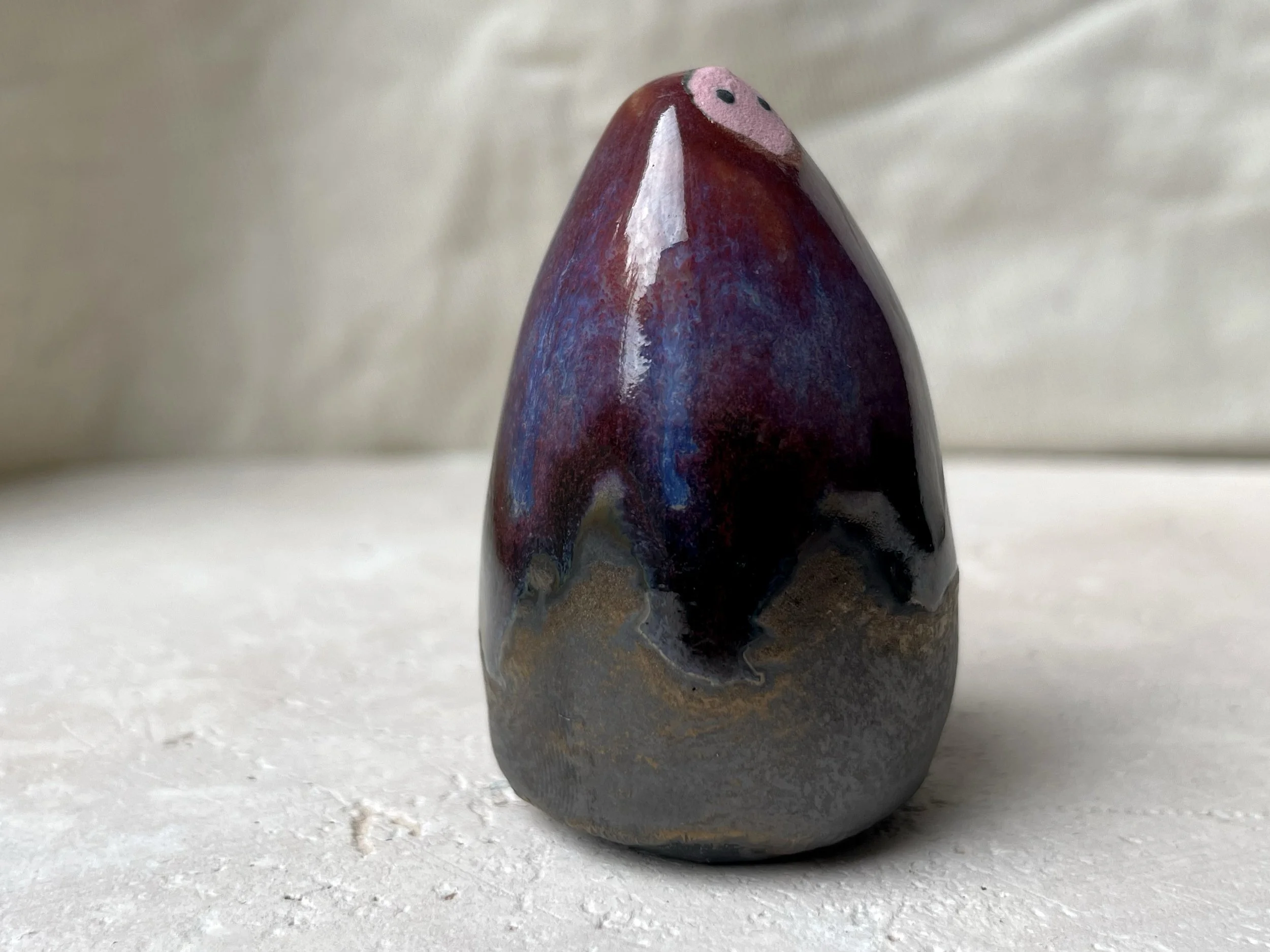 Red, purple, black, gold and pink handmade figurative ceramic sculpture with glossy drippy floating glaze