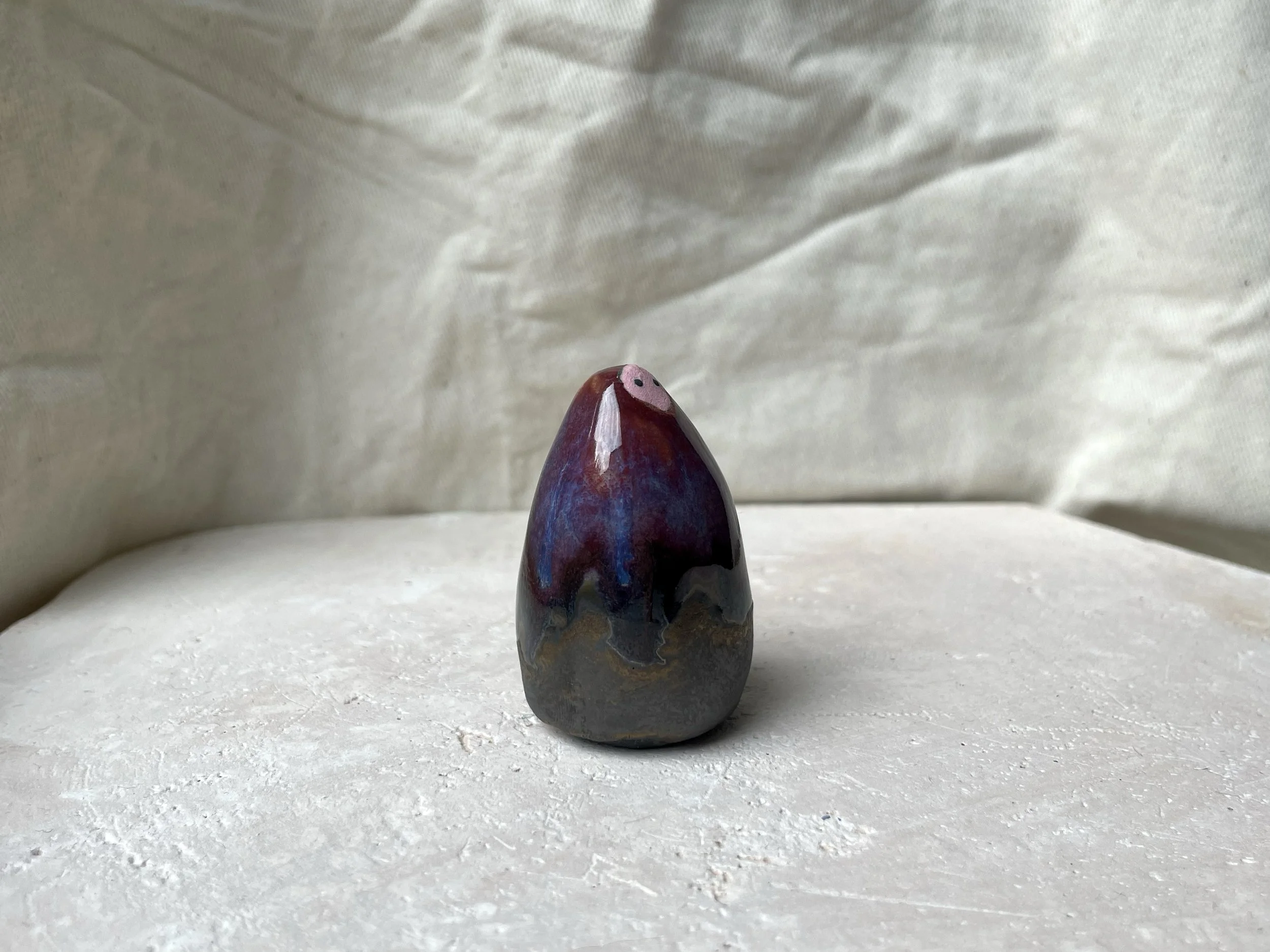 Red, purple, black, gold and pink handmade figurative ceramic sculpture with glossy drippy floating glaze