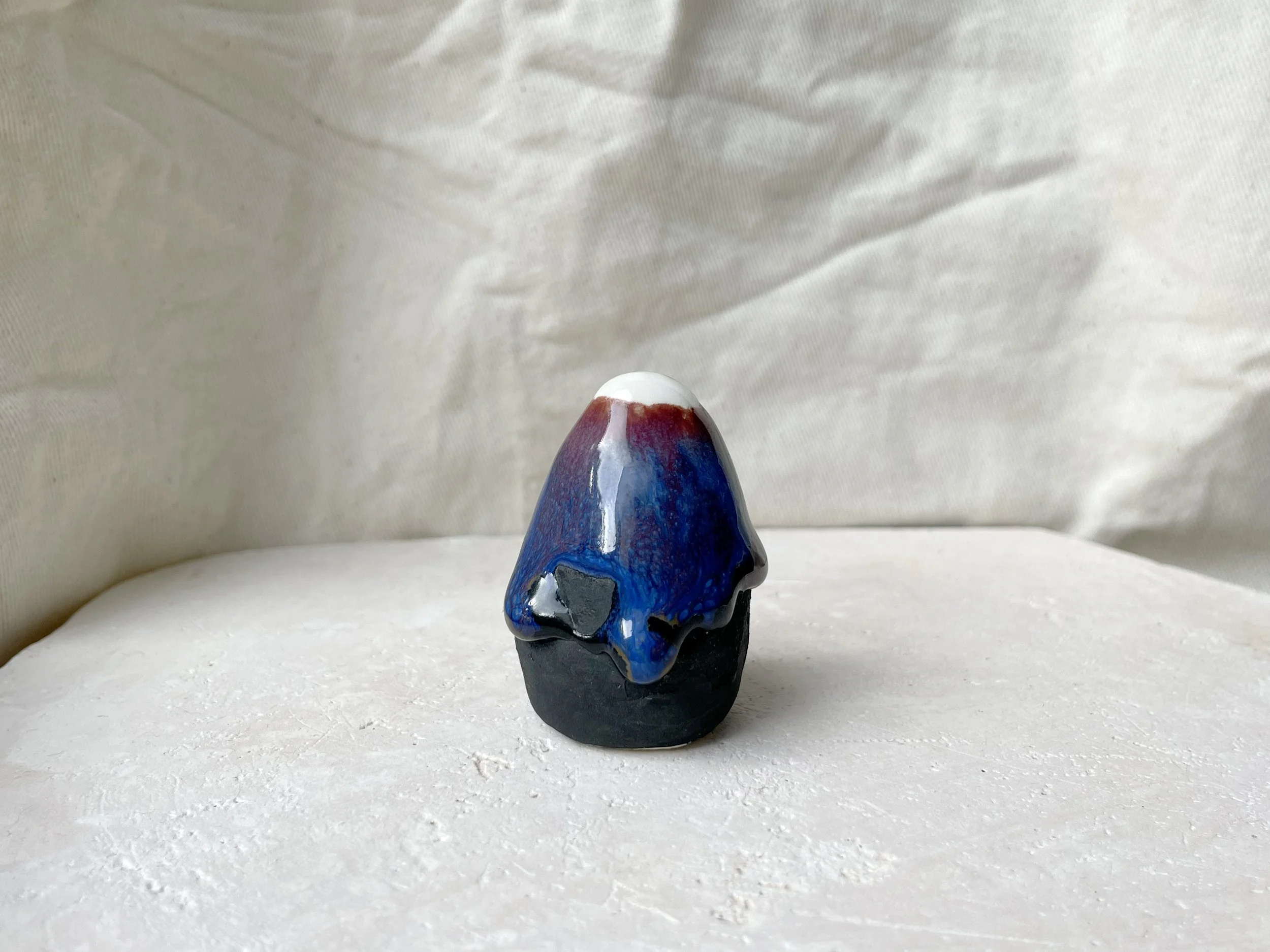 black, brown, red, blue and green handmade figurative ceramic sculpture with matte and glossy floating glaze