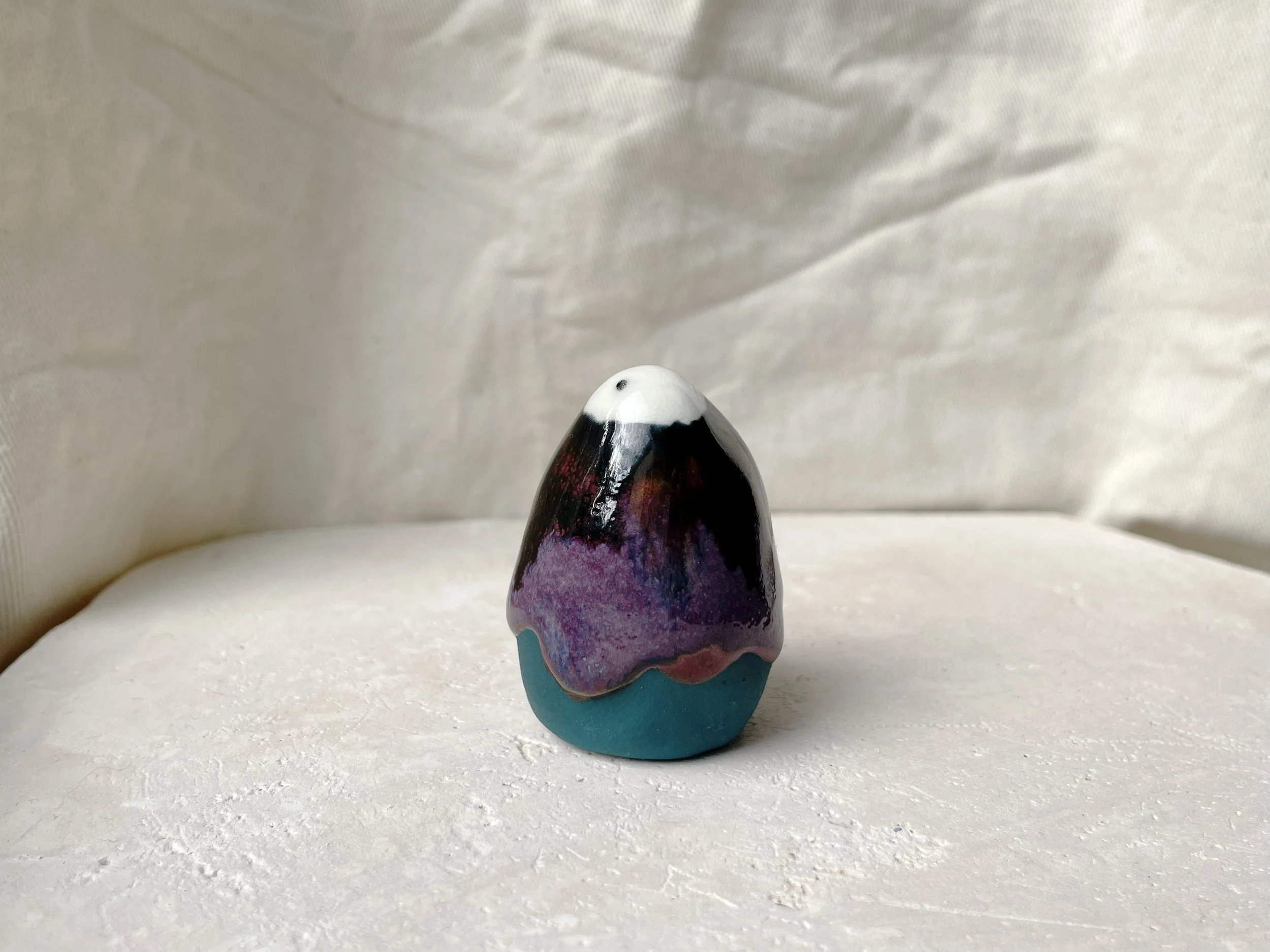 Black, purple, green and red handmade figurative ceramic sculpture with glossy drippy floating glaze