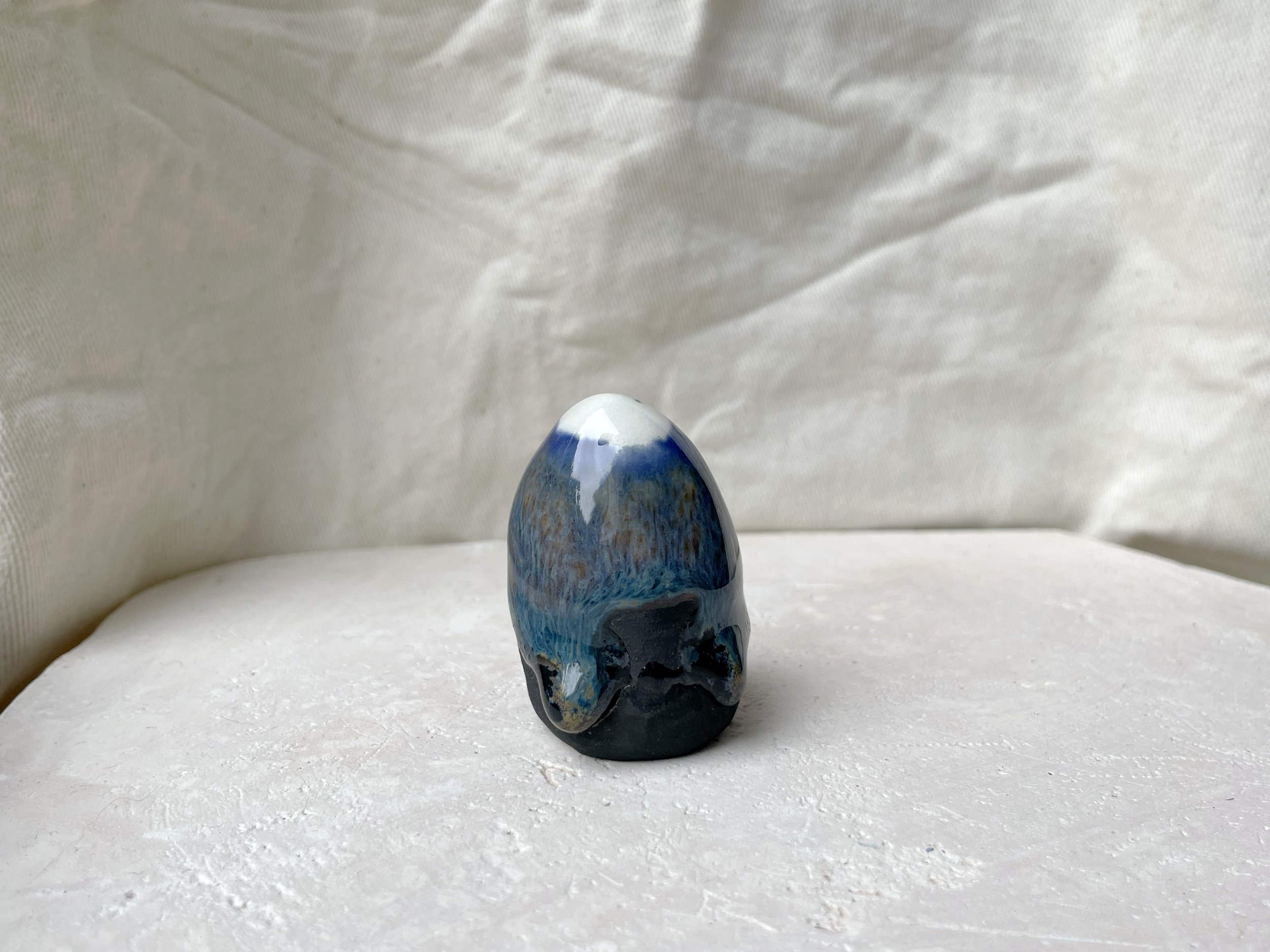 Blue, orange, black handmade figurative ceramic sculpture with glossy runny floating glaze