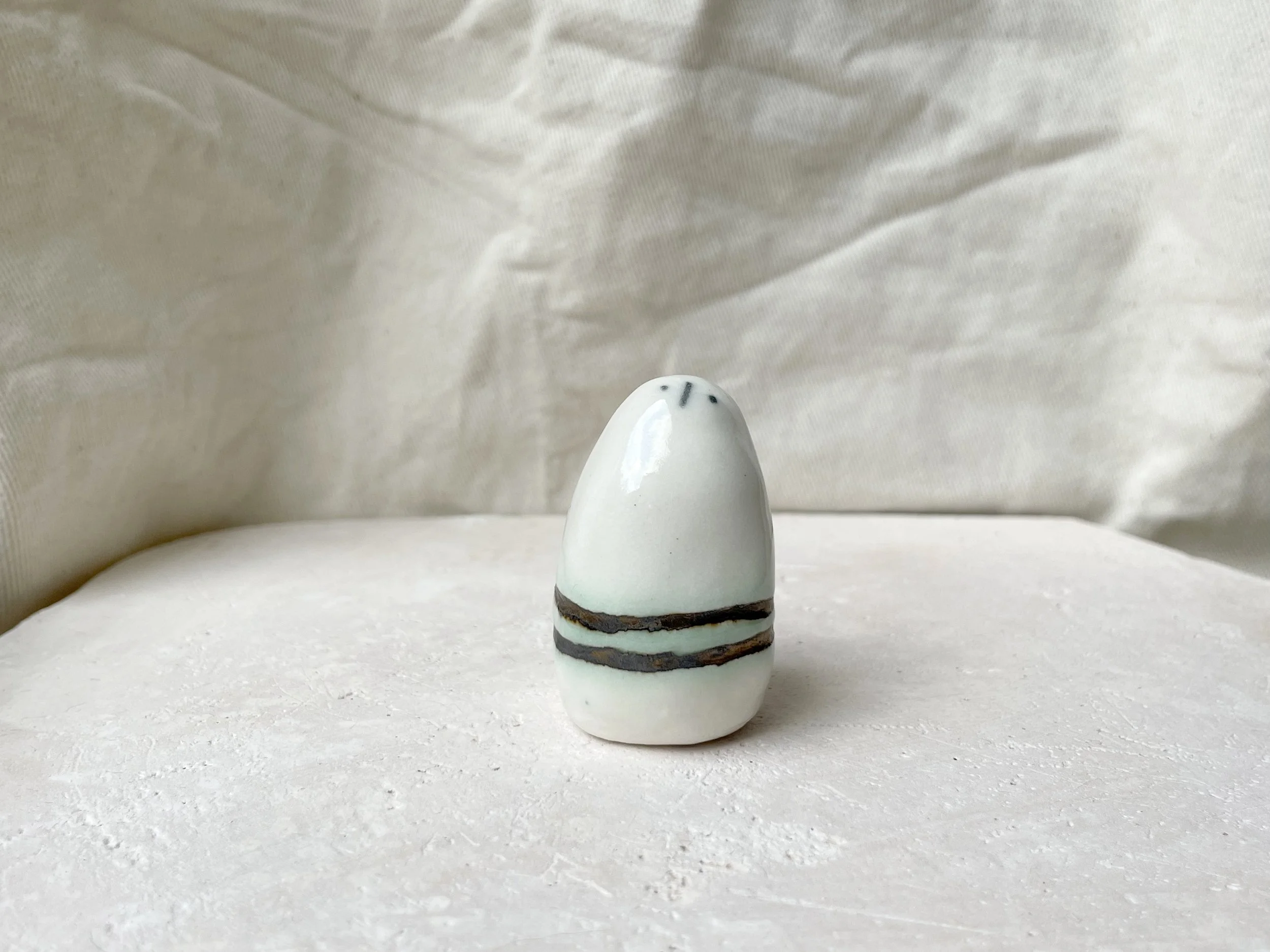 White and gold glossy handmade figurative ceramic sculpture with metallic glaze and hint of green