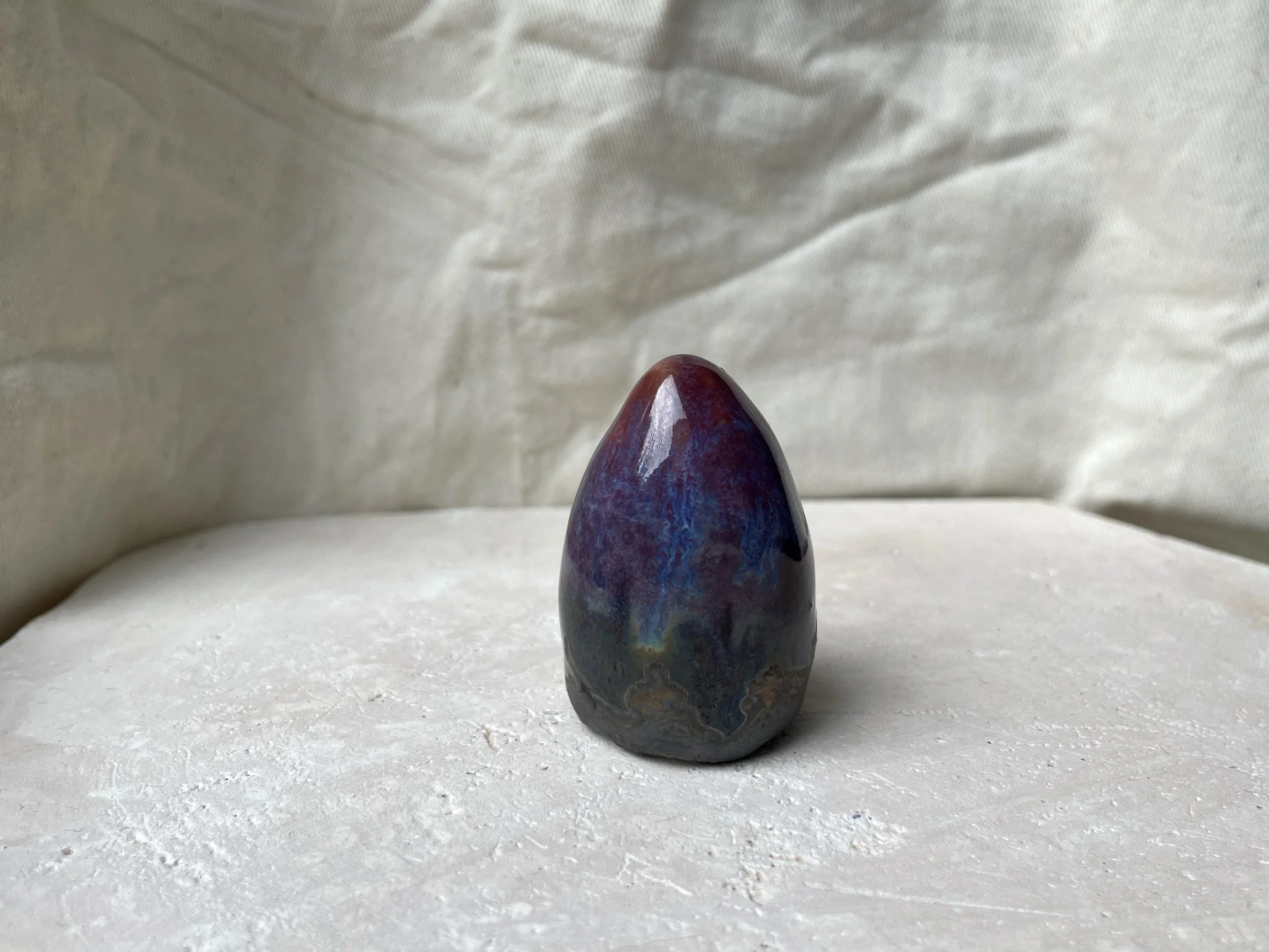 Red, purple, black, gold and pink handmade figurative ceramic sculpture with glossy drippy floating glaze