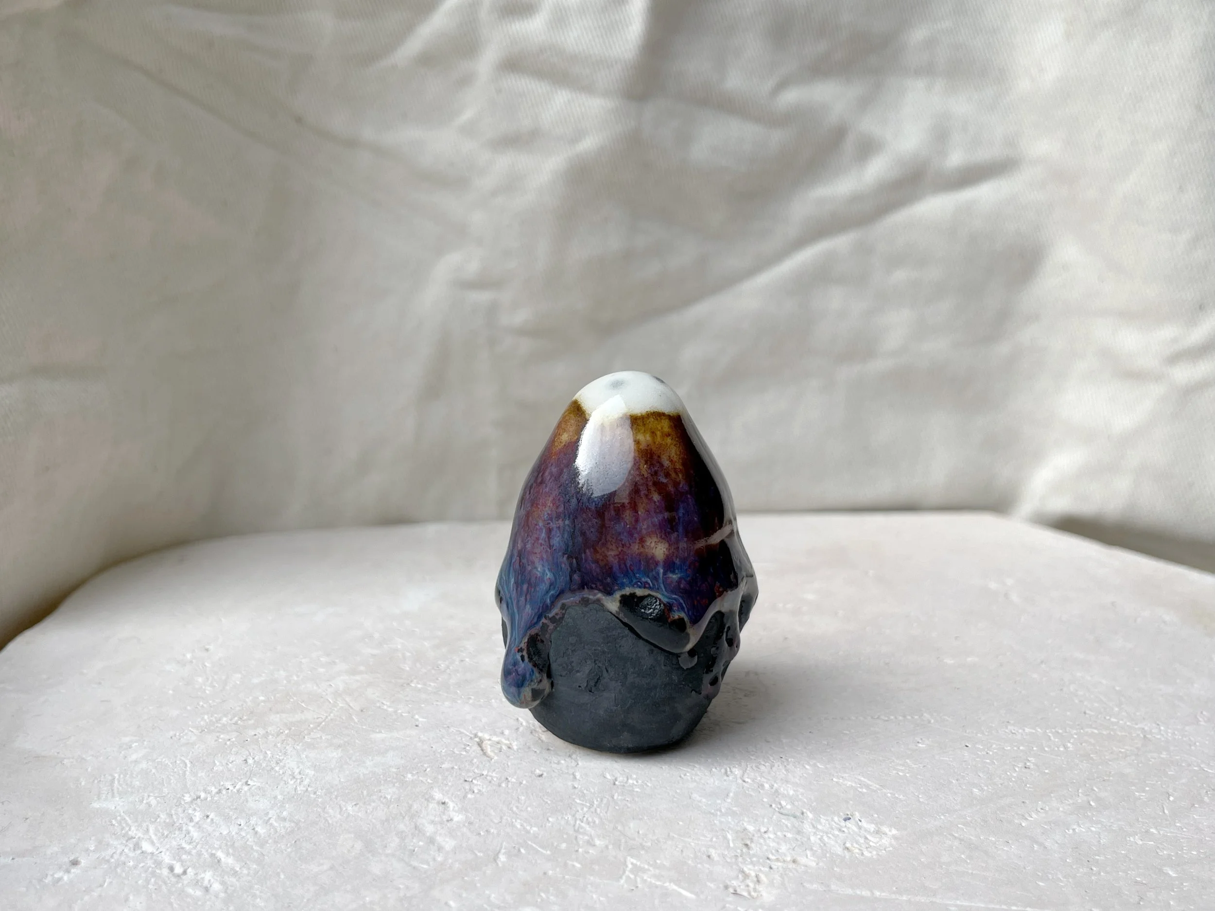 Brown, purple, blue and black handmade figurative ceramic sculpture with glossy runny floating glaze