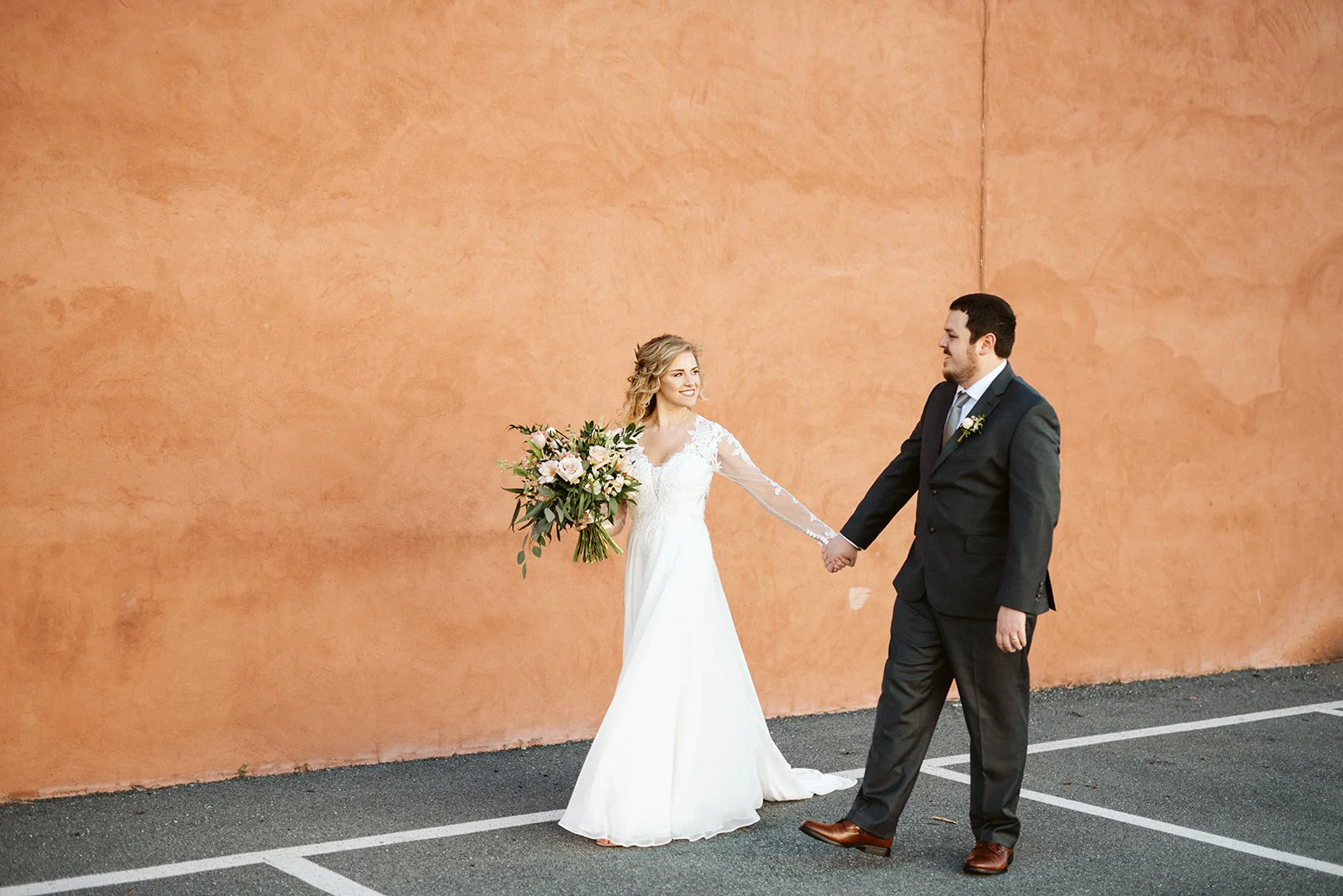 Cork Factory Hotel, Lancaster, PA Wedding - Bride and Groom walking past the peach wall on the exterior of the Cork Factory Hotel property.