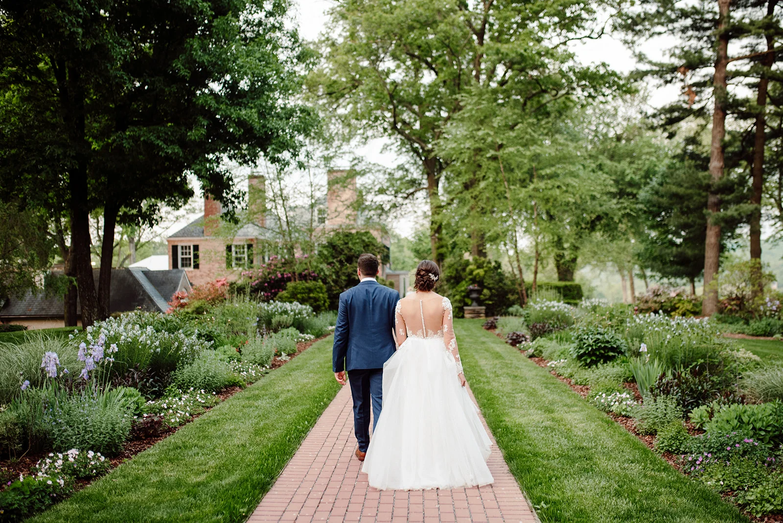 A bride and groom walk through the gardens during their Drumore Estate wedding.