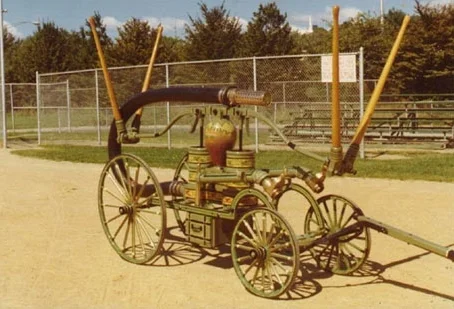 1893 Van Duyne Hand Pumper On August 23, 1893, the Common Council passed a resolution that authorized the purchase of a hand-operated Pumping Engine, to be manufactured by Simeon Van Duyne, to cost $200.00 and 300 feet of hose to be stored in a suitable place in West Boonton with a suitable alarm. On September 13 of that year, Harmony Hose & Engine Company # 2 was assigned the engine built by Simeon Van Duyne, of Boonton. Before the firehouse was completed, the engine and the 300 feet of hose was housed in Theodore Ringlieb's barn on West Main Street. When they moved into their new firehouse, they realized that more equipment would have to be purchased. Harmony Company purchased a hose reel for $90.00 and a chiefs leather helmet (purchased in Seneca Falls, NY) with a blue cord and tassel for only $5.25 without any tax! In 1894, the Harmony Company bought a lot on the corner of Oak Street and Highland Avenue for the enormous sum of $70.00 for their own firehouse. The firehouse itself was built at a total cost of $560.00. The Van Duyne Hand Pumper was originally built on a wood chassis which did not survive the fire. The pumping engine received considerable damage from the fire and this was repaired by Mr. Oscar Whitehead. The chassis was rebuilt with iron and was repainted and continued to serve the Town. The pumper was returned to service in excellent condition with improvements and changes and it saw extensive service prior to the advent of our motorized apparatus. The hand pumper was restored and is currently housed in the New Jersey Firemen's Home Museum.