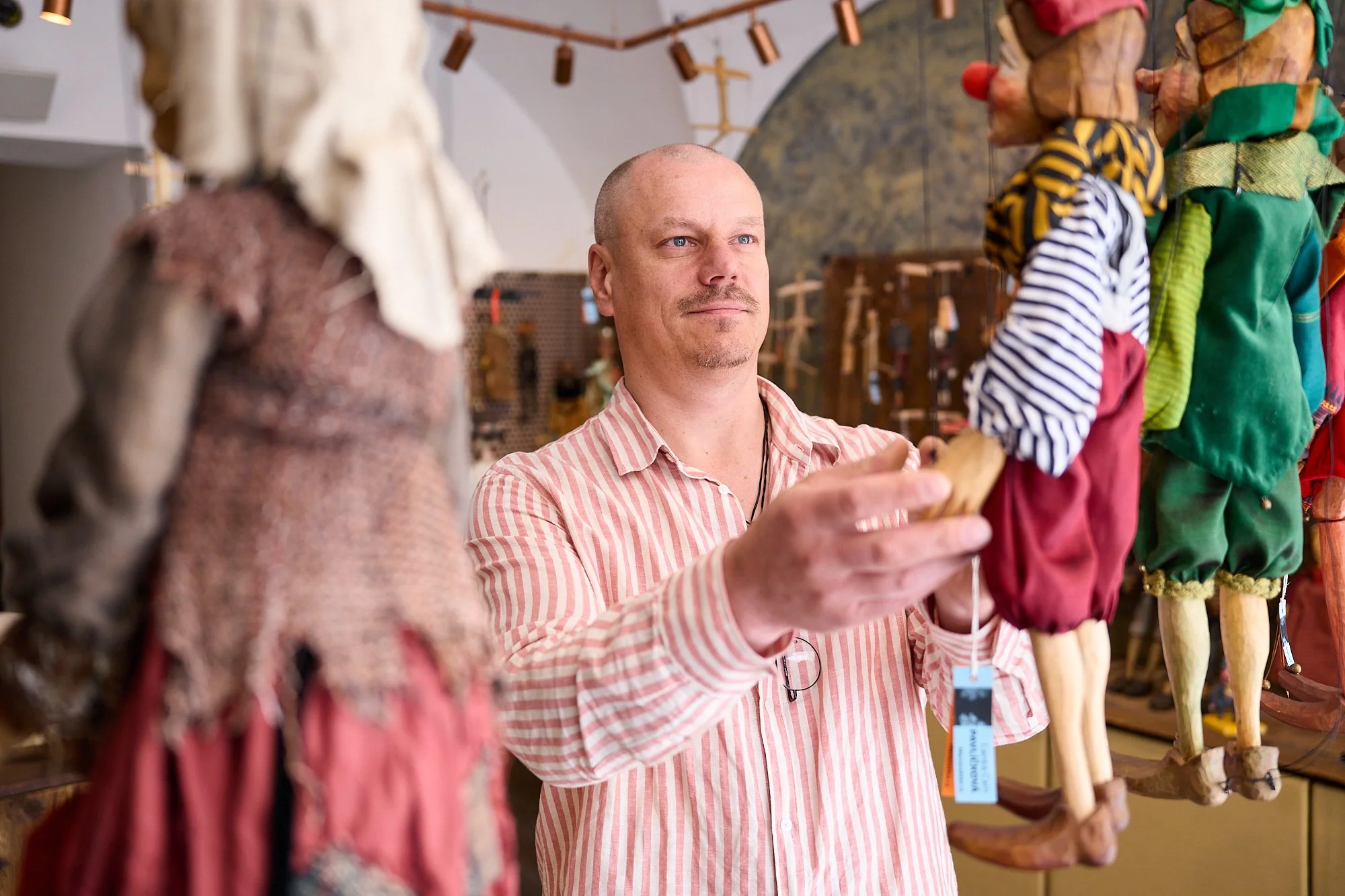  Petr Puppeteer, the owner of Czech Marionettes in Prague inspecting some of the many puppets sold at the shop in Prague 1, Czechia.  