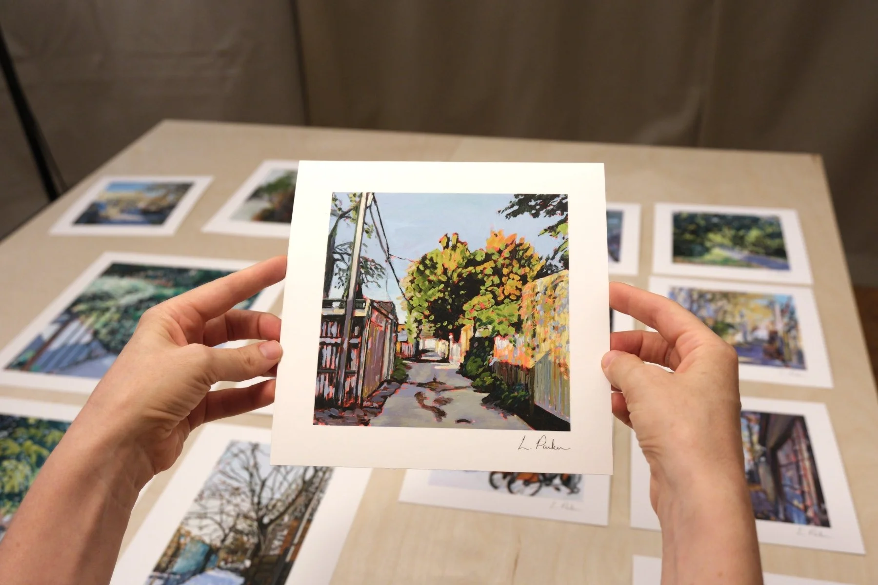 Leslie Parker holding a fine art print of a grey Leslieville laneway in winter