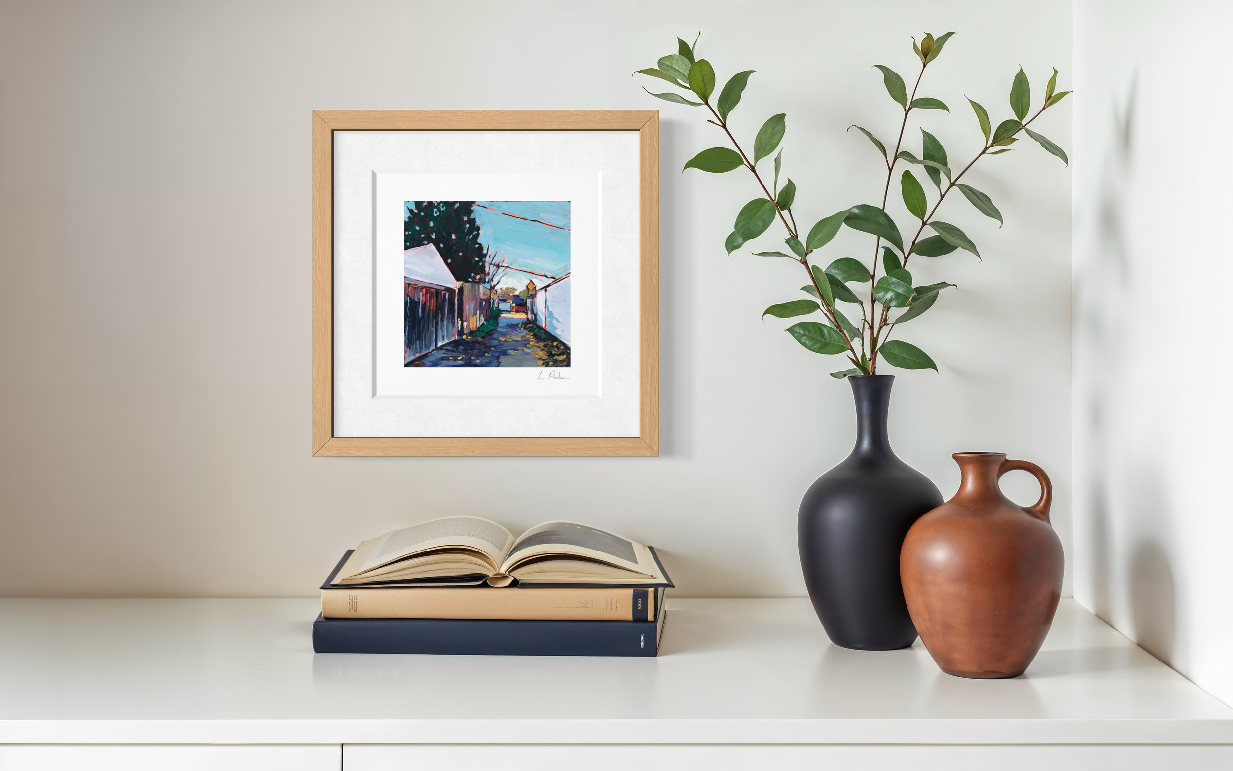 a Leslieville laneway in fall — framed Toronto art print hanging on a wall with a book below
